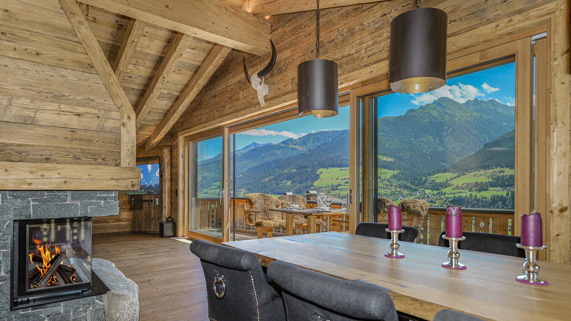 Essbereich mit Kamin, Holzbalken und Panoramablick auf die majestätischen Berge.