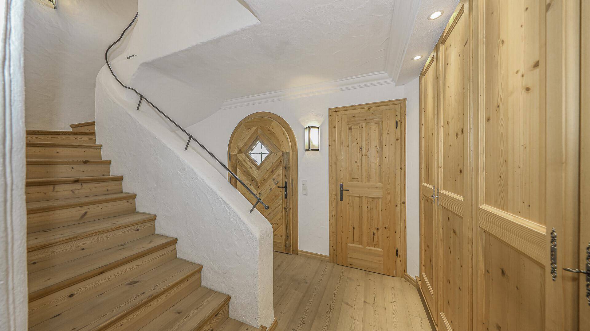Treppenhaus mit Holzstufen und geschwungener Wand, führt zu den oberen Etagen.