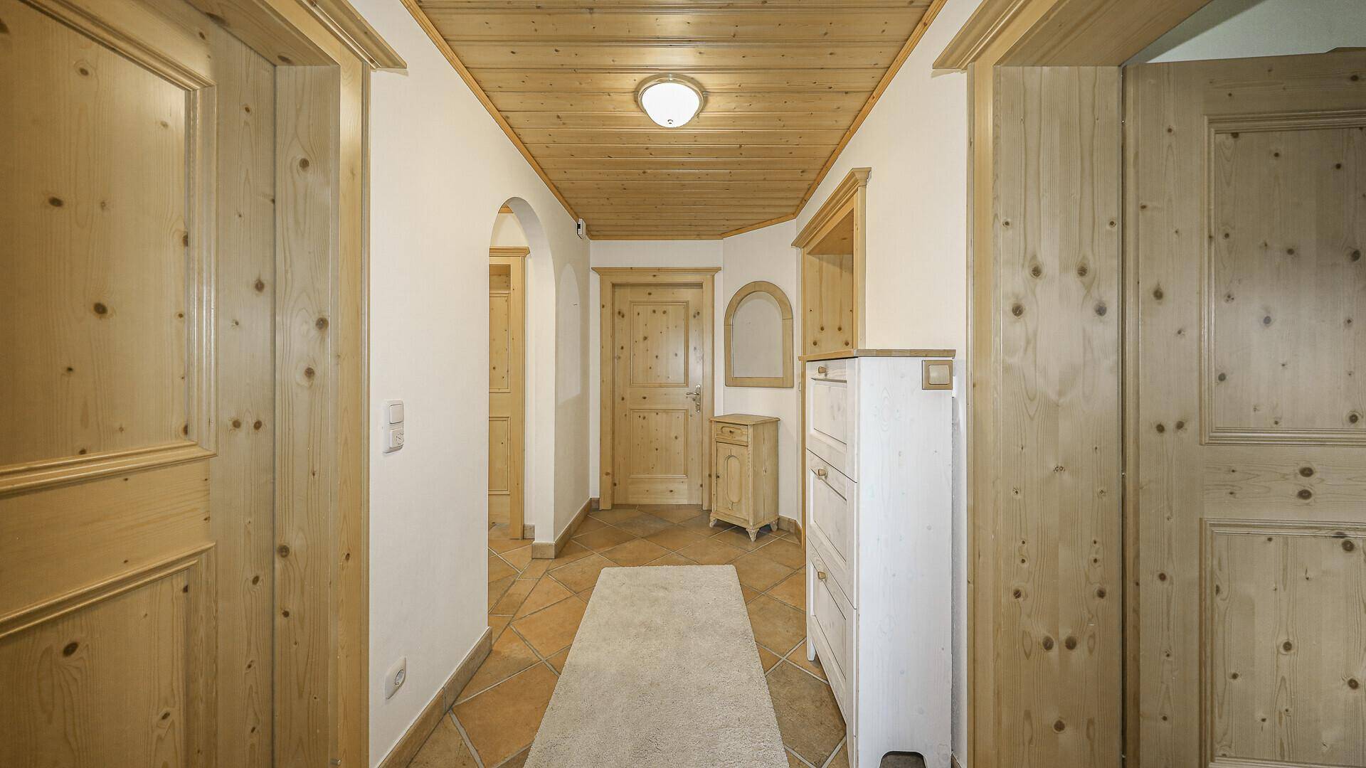 Heller Flur mit Holzdecke, Terrakottafliesen und traditionellen Holzmöbeln.