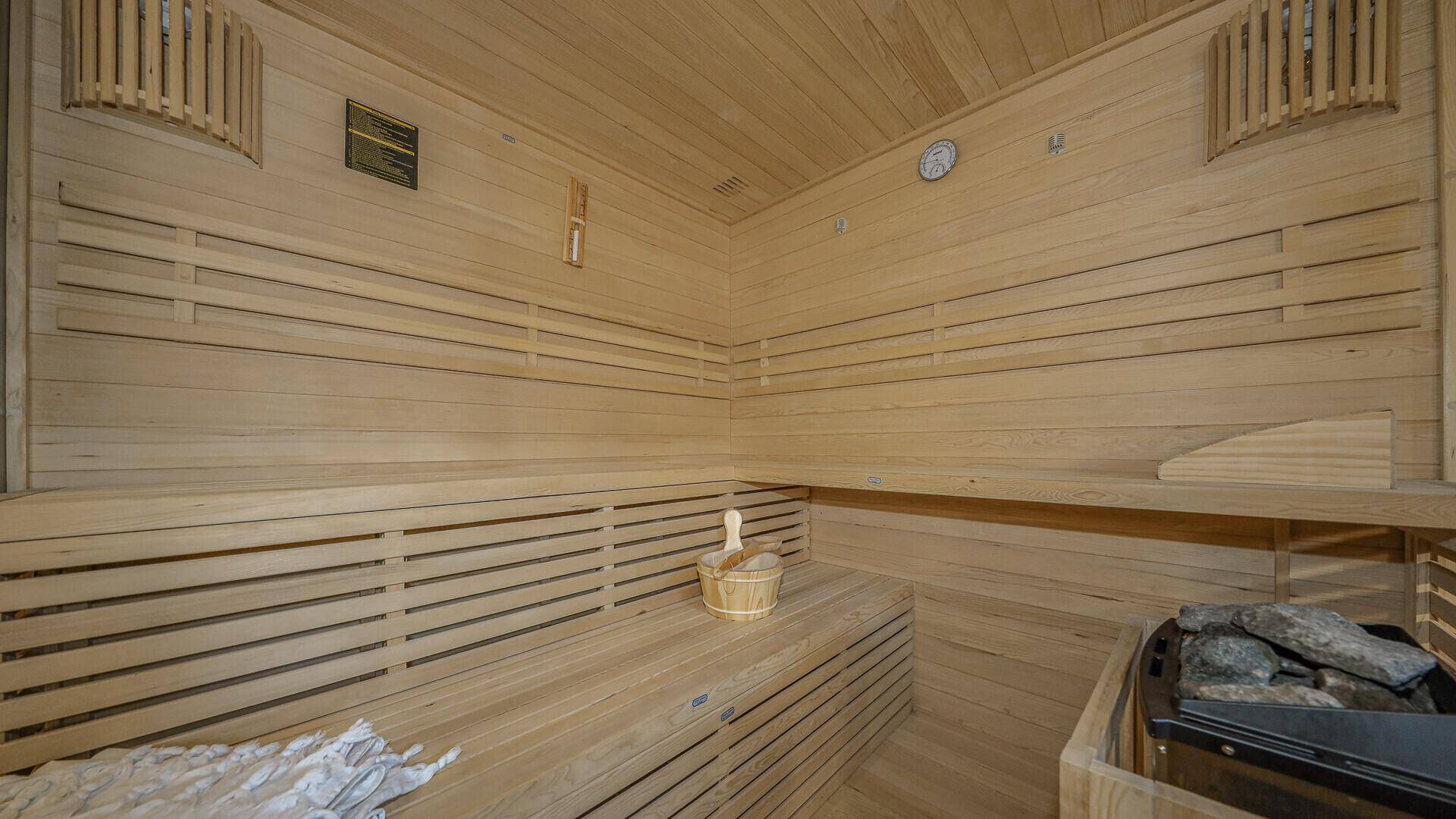Innenansicht einer traditionellen Holzsauna mit mehrstufigen Bänken und Saunaofen.