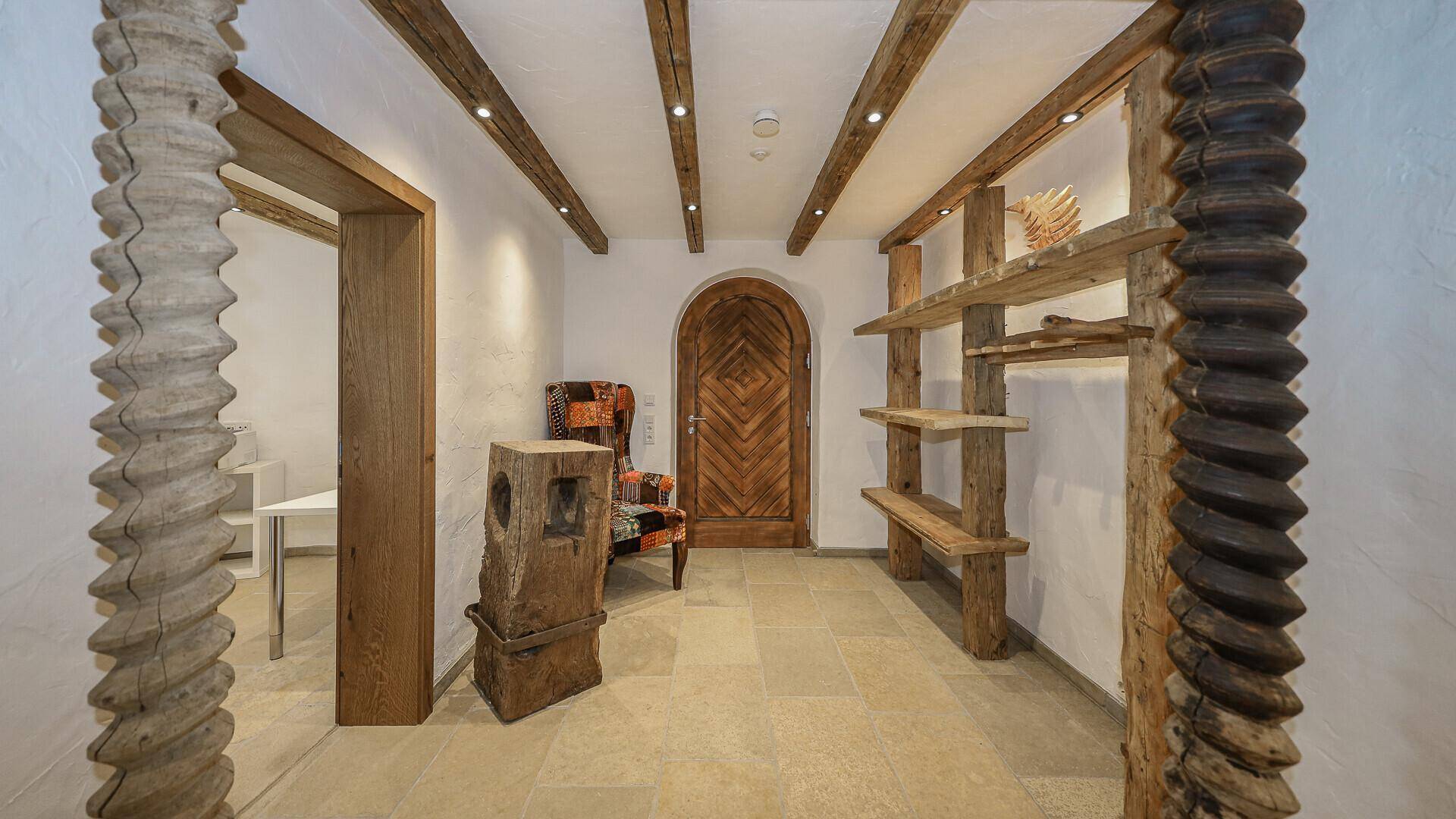 Eingangsbereich mit Holzbalken, Steinboden und rustikalen Holzelementen.