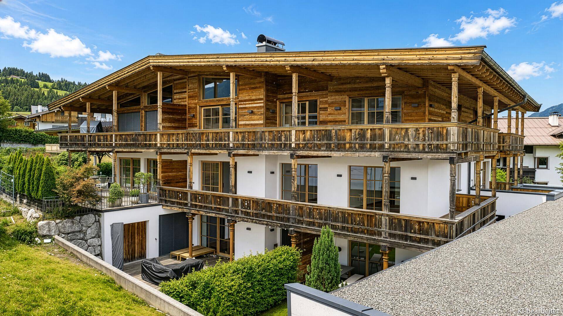 Traditionelles Holzhaus im alpinen Stil mit mehreren Balkonen und gepflegtem Garten.