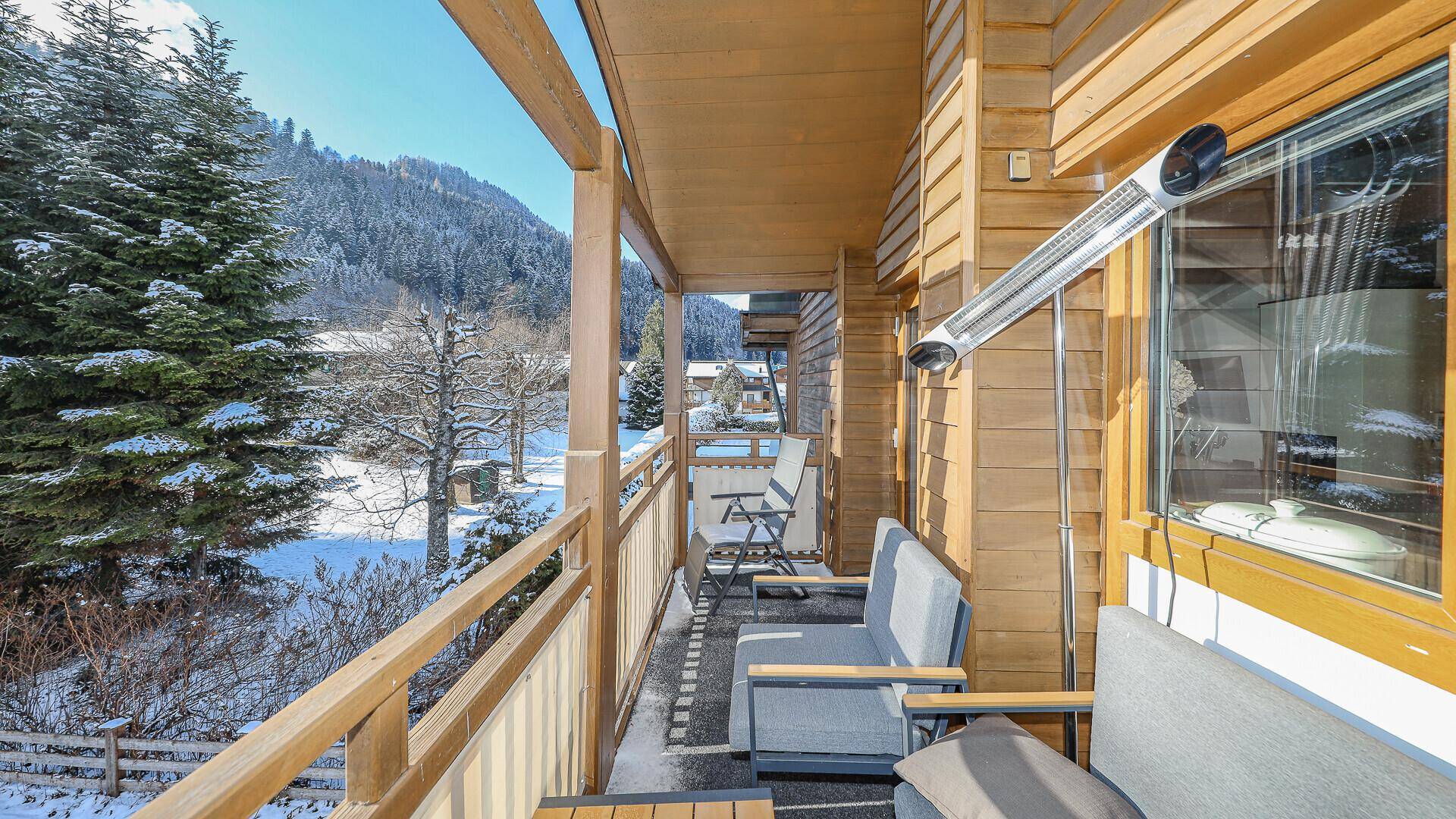 Gemütlicher Balkon mit Sitzgelegenheiten und Blick auf die verschneite Berglandschaft.