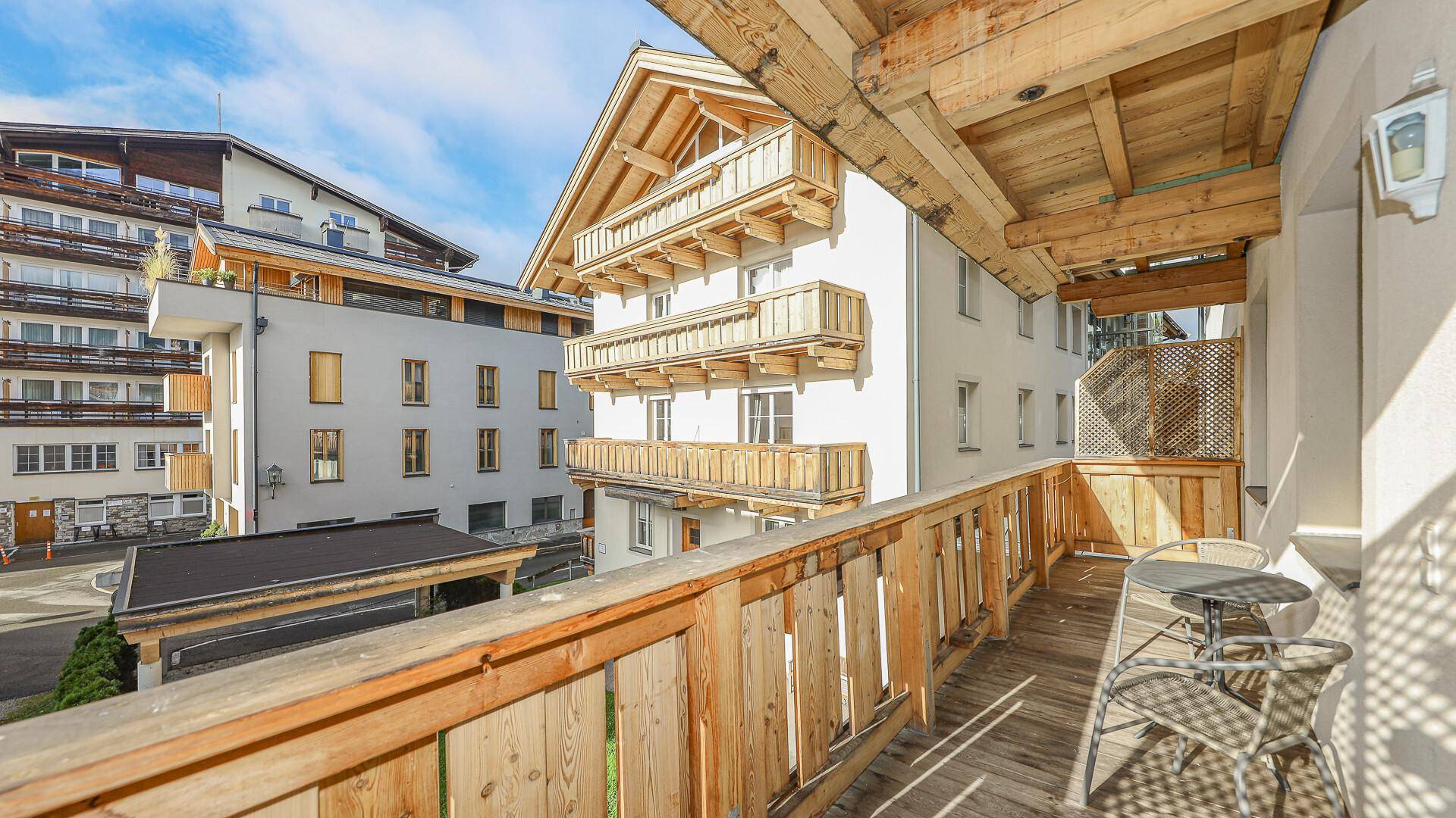 Geräumiger Balkon mit Holzgeländer und Blick auf die traditionelle Architektur der Umgebung.