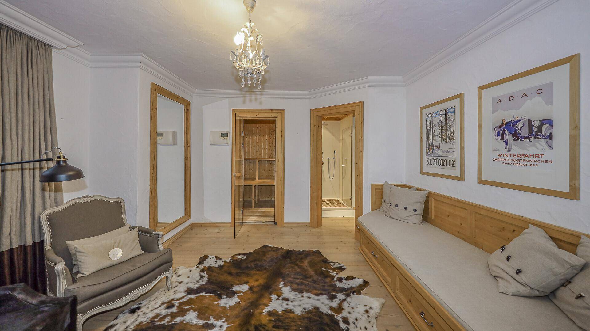 Helles Schlafzimmer mit Tagesbett, Spiegel und Zugang zu Sauna und Dusche.