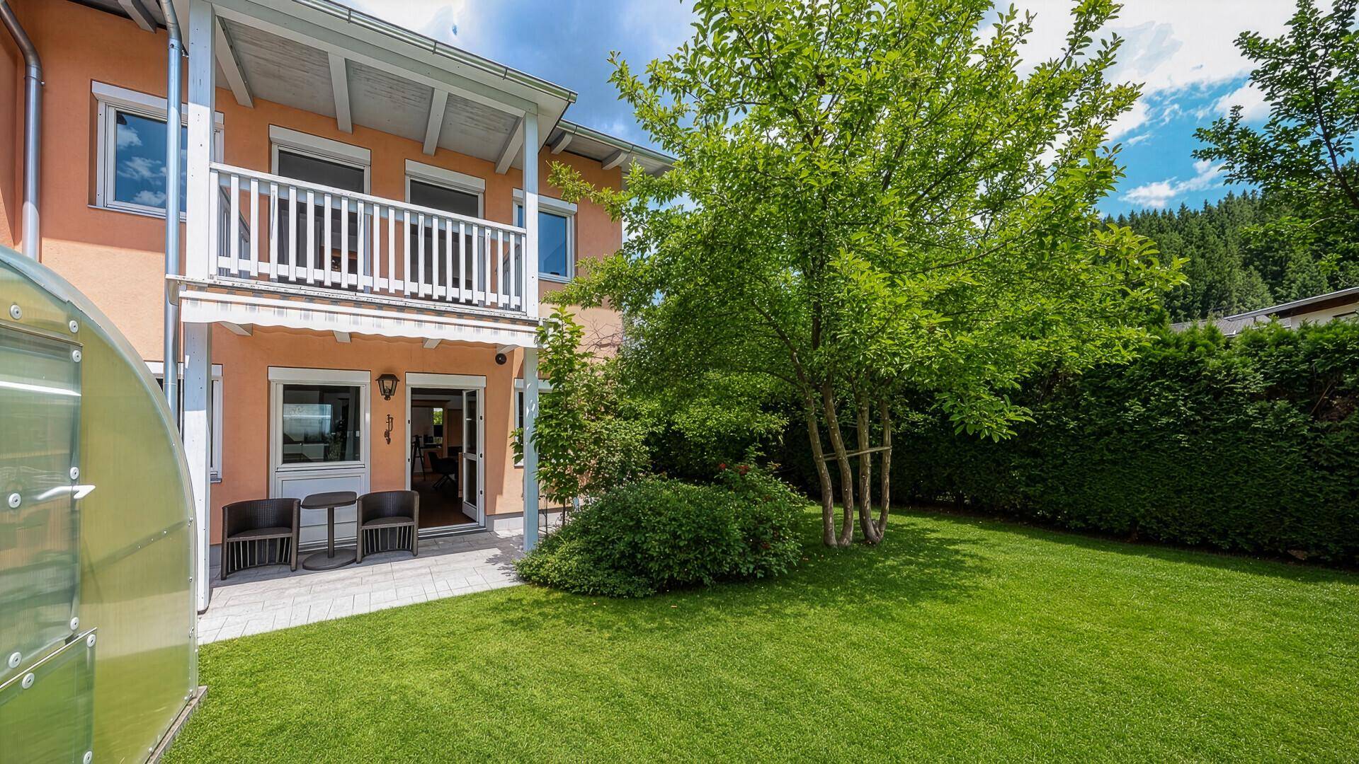 Rückseite des Hauses mit Balkon, Terrasse und großem, gepflegtem Gartenbereich.
