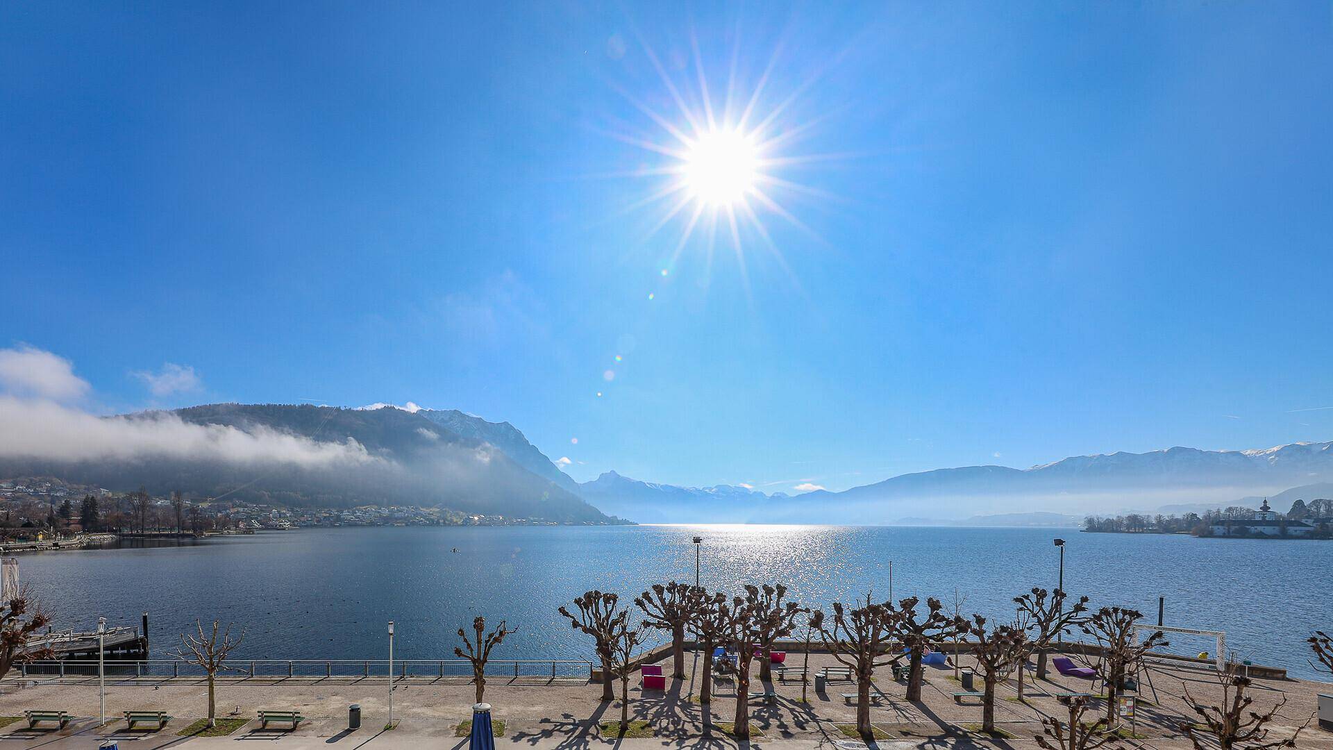 Weitläufiger Blick über den See und die majestätische Bergkette unter strahlend blauem Himmel.