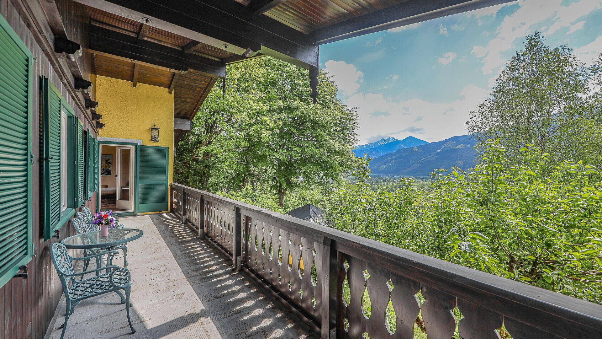 Geräumiger Balkon mit traditionellem Holzgeländer und weitem Blick ins Grüne und die Berge.