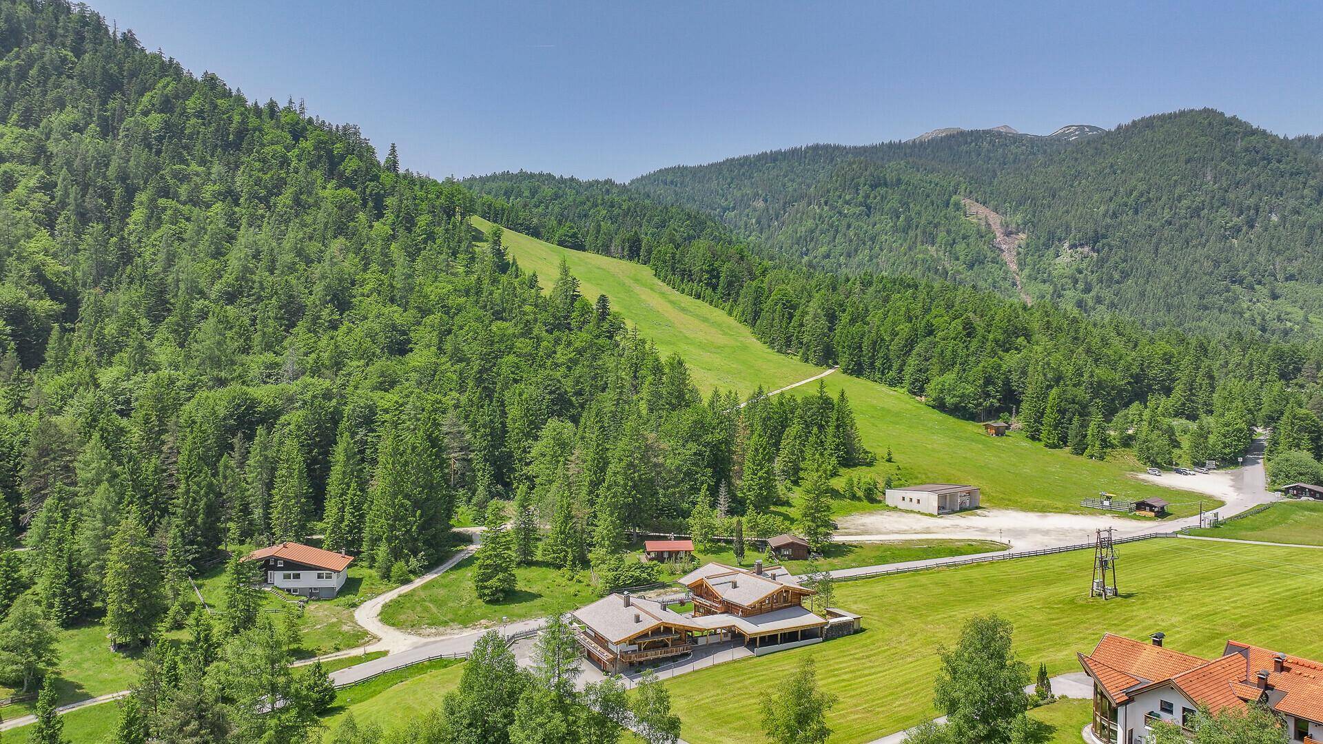 Luftaufnahme des Chalet-Anwesens in einer malerischen Berglandschaft mit Wald und Skipiste.