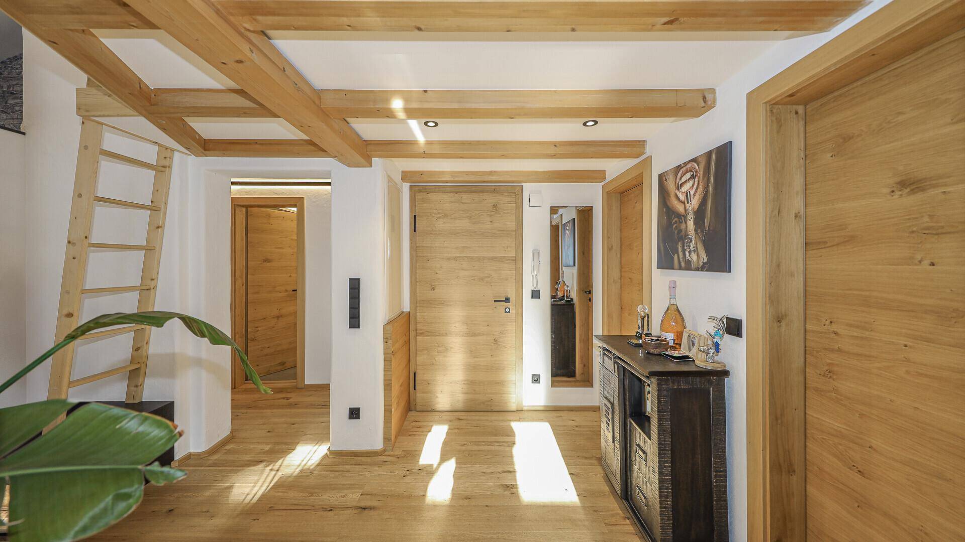 Heller Flur mit Holzbalken an der Decke und Holzboden.
