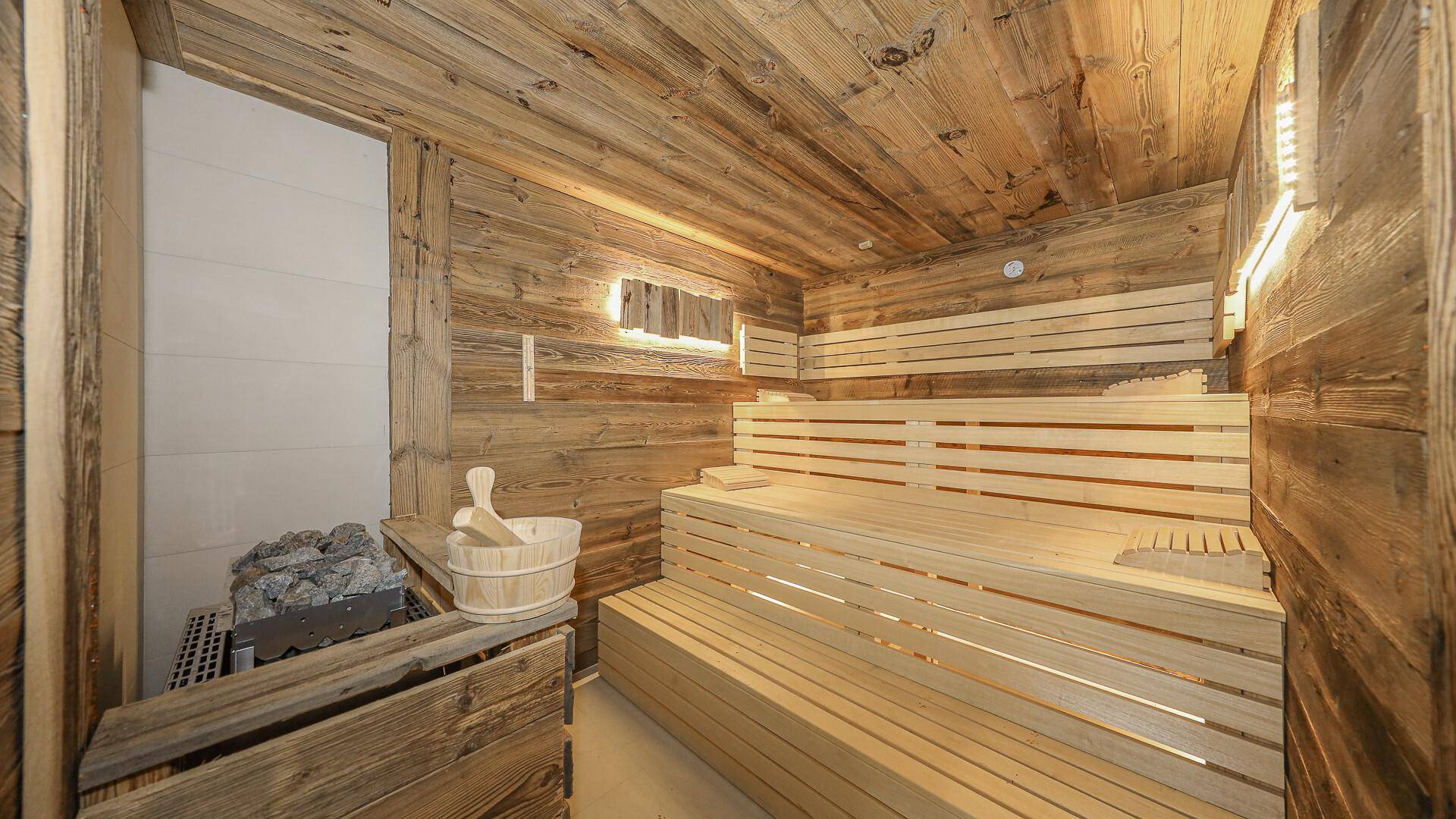 Traditionelle Holzsauna mit mehreren Bänken und Saunaofen für Entspannung.