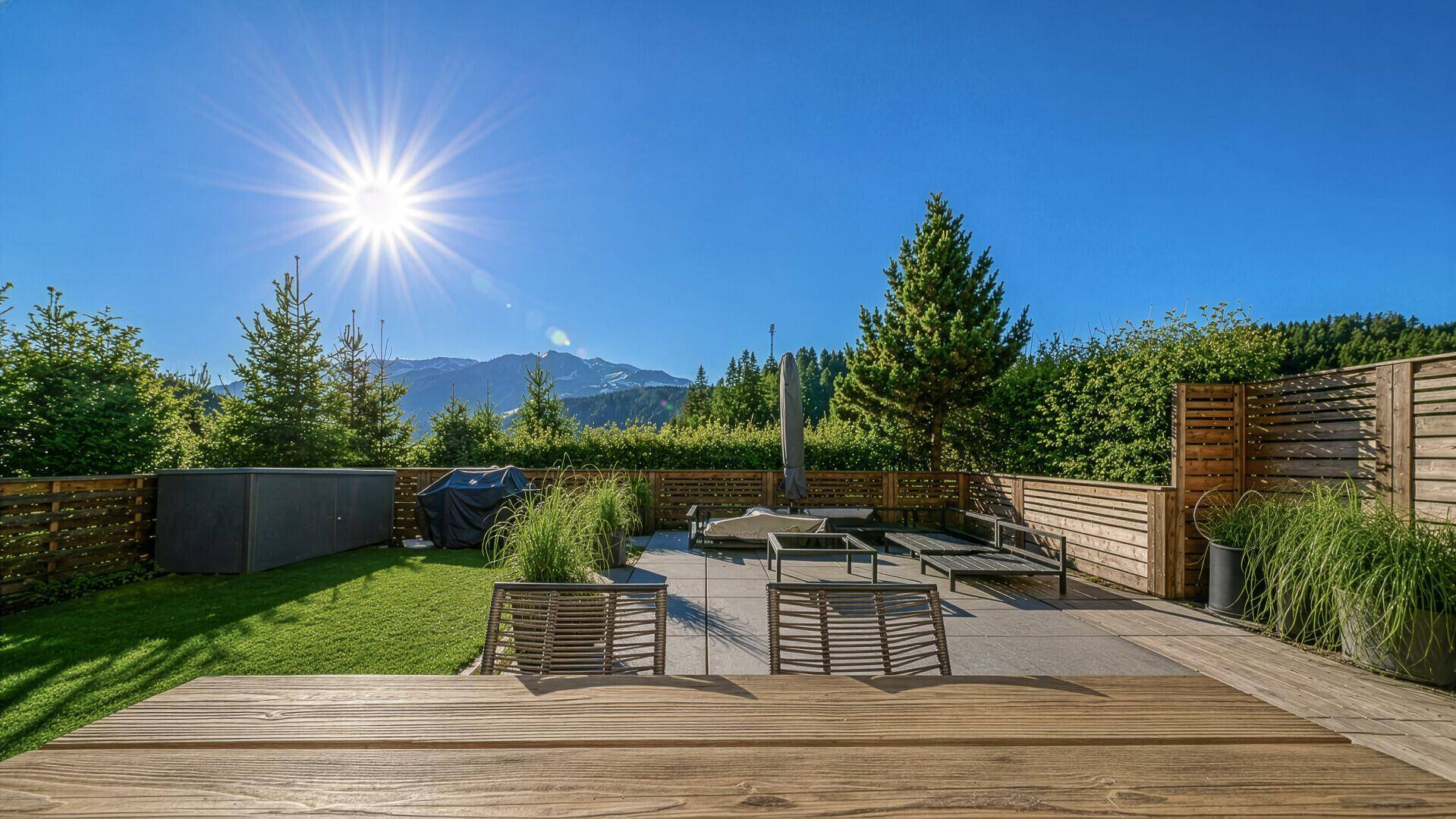Weitläufiger Gartenbereich mit moderner Terrassengestaltung und bequemen Lounge-Möbeln unter strahlend blauem Himmel.