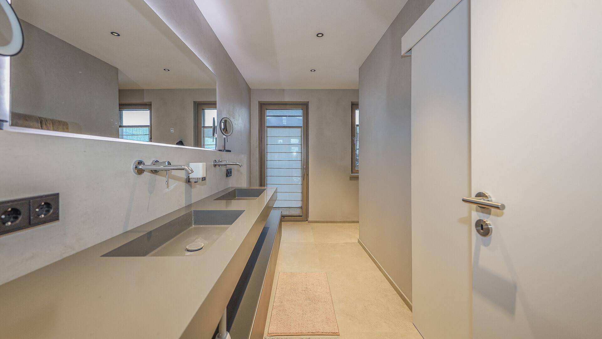 Modernes Badezimmer mit Doppelwaschbecken, großem Spiegel und minimalistischer Gestaltung.