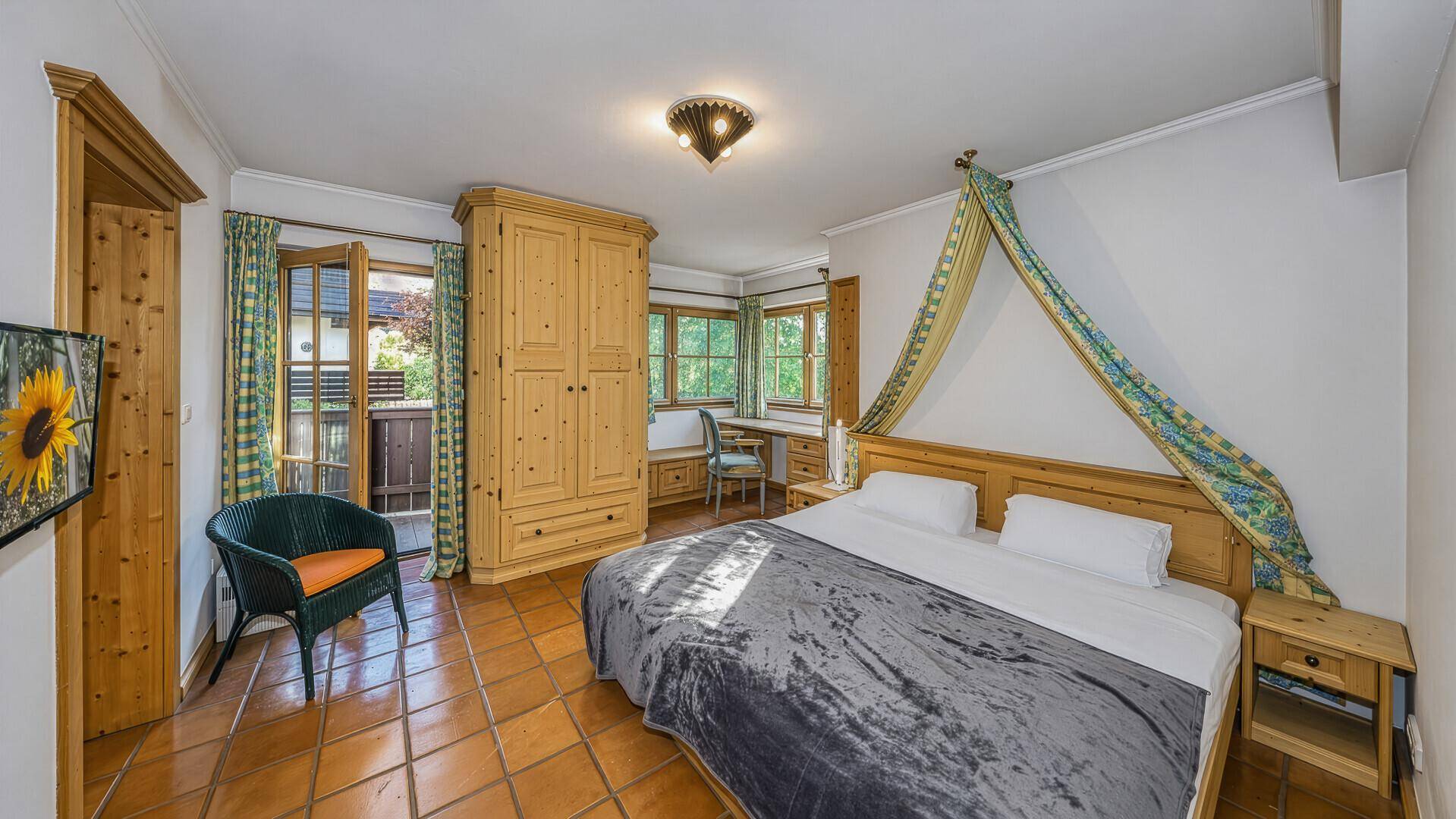 Gemütliches Schlafzimmer mit Doppelbett, Holzschrank und direktem Zugang zum Balkon.