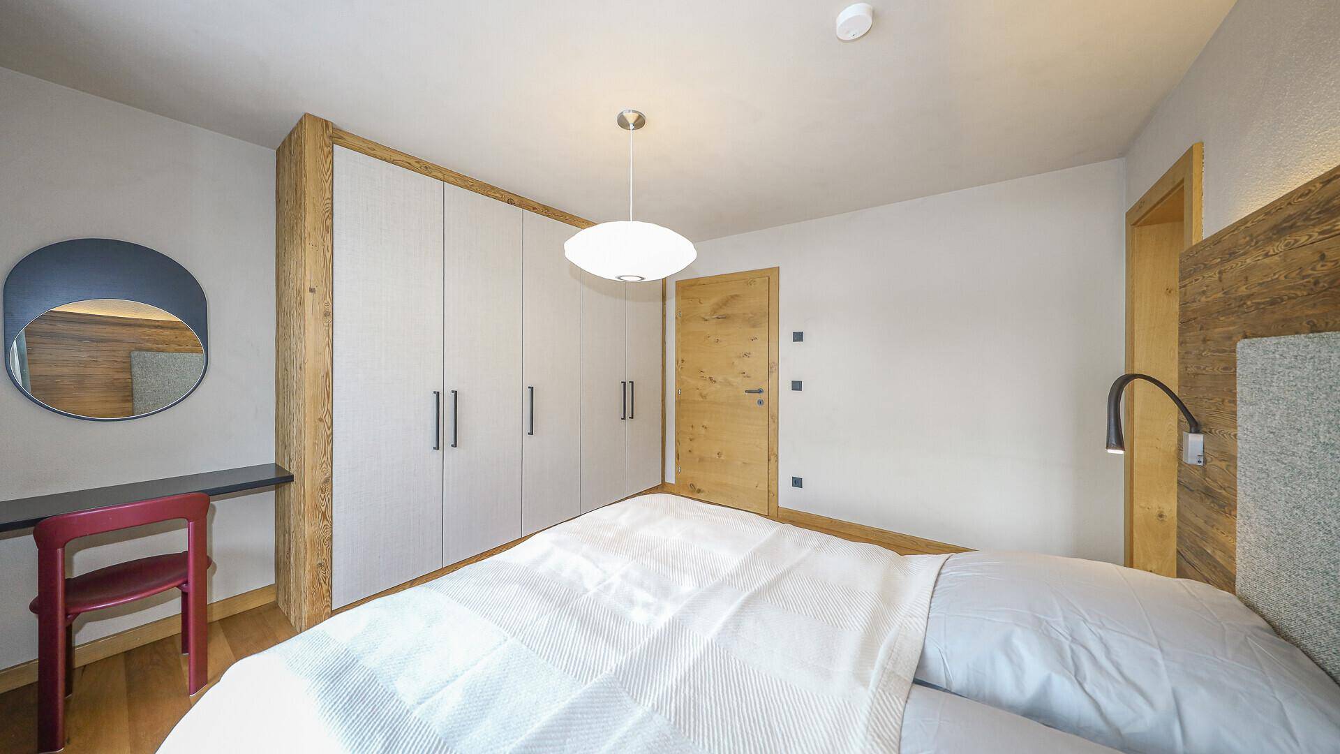 Modernes Schlafzimmer mit Holzboden, Einbauschränken und schlichter, eleganter Einrichtung.