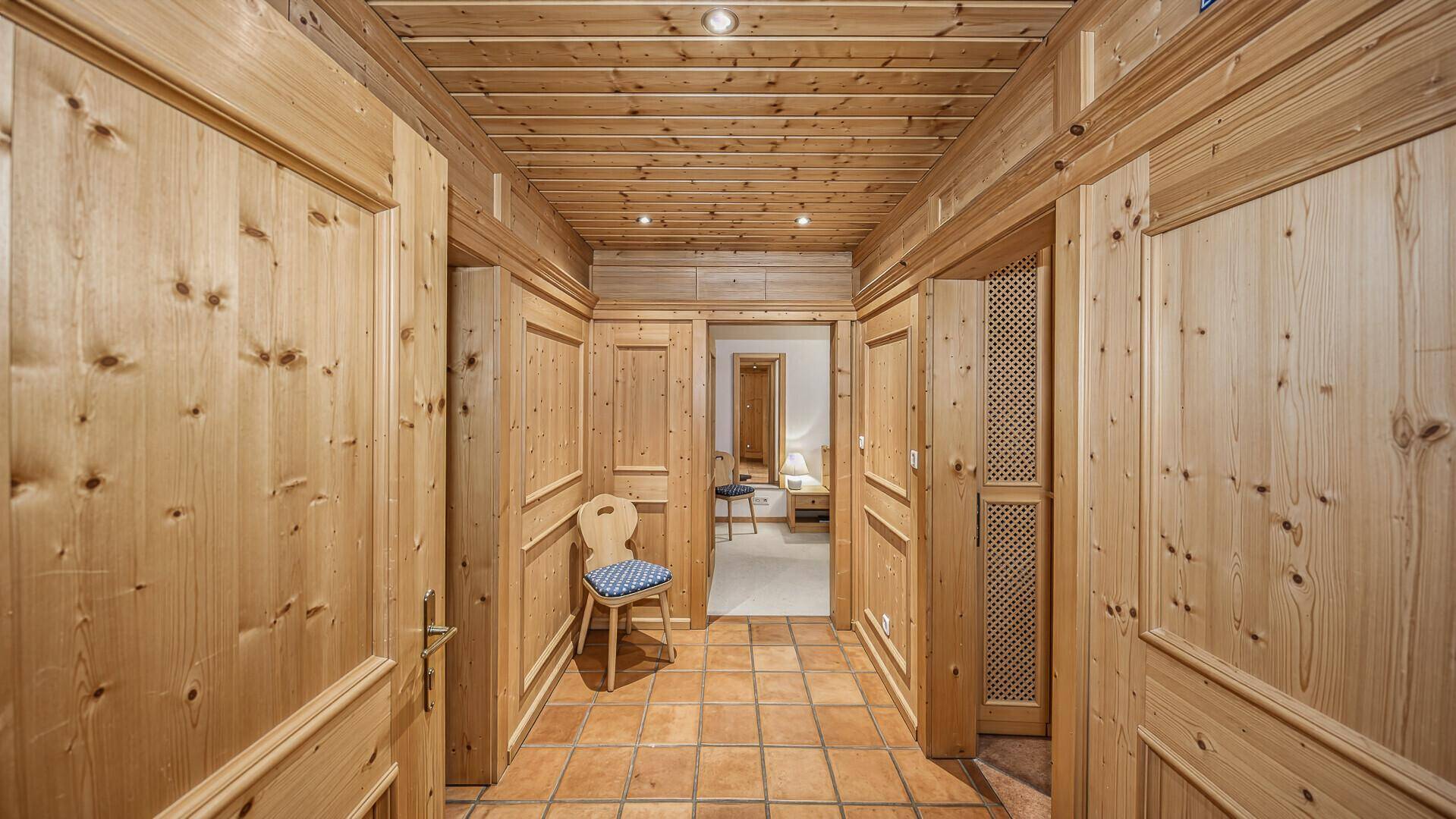 Traditioneller Flur mit Holzvertäfelung an Wänden und Decke sowie Terrakotta-Fliesenboden.