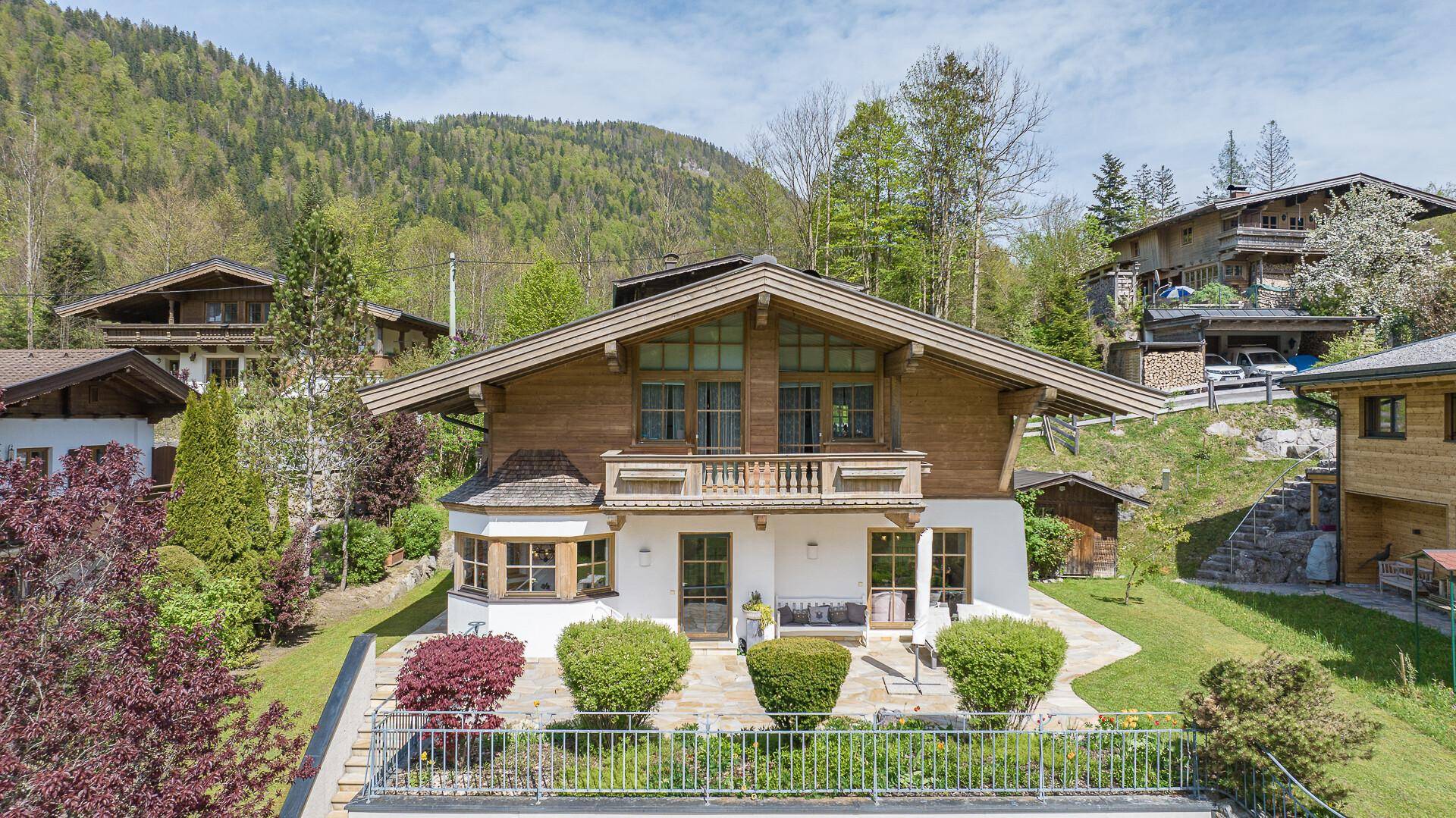 Vorderansicht des Chalets mit traditioneller Holzfassade, kleinem Garten und Bergblick.
