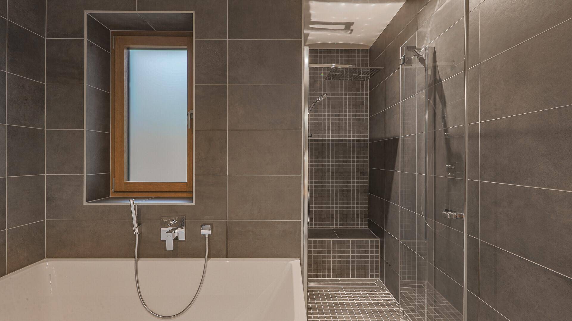 Modernes Badezimmer mit großer Dusche, Badewanne und Fenster für natürliches Licht.