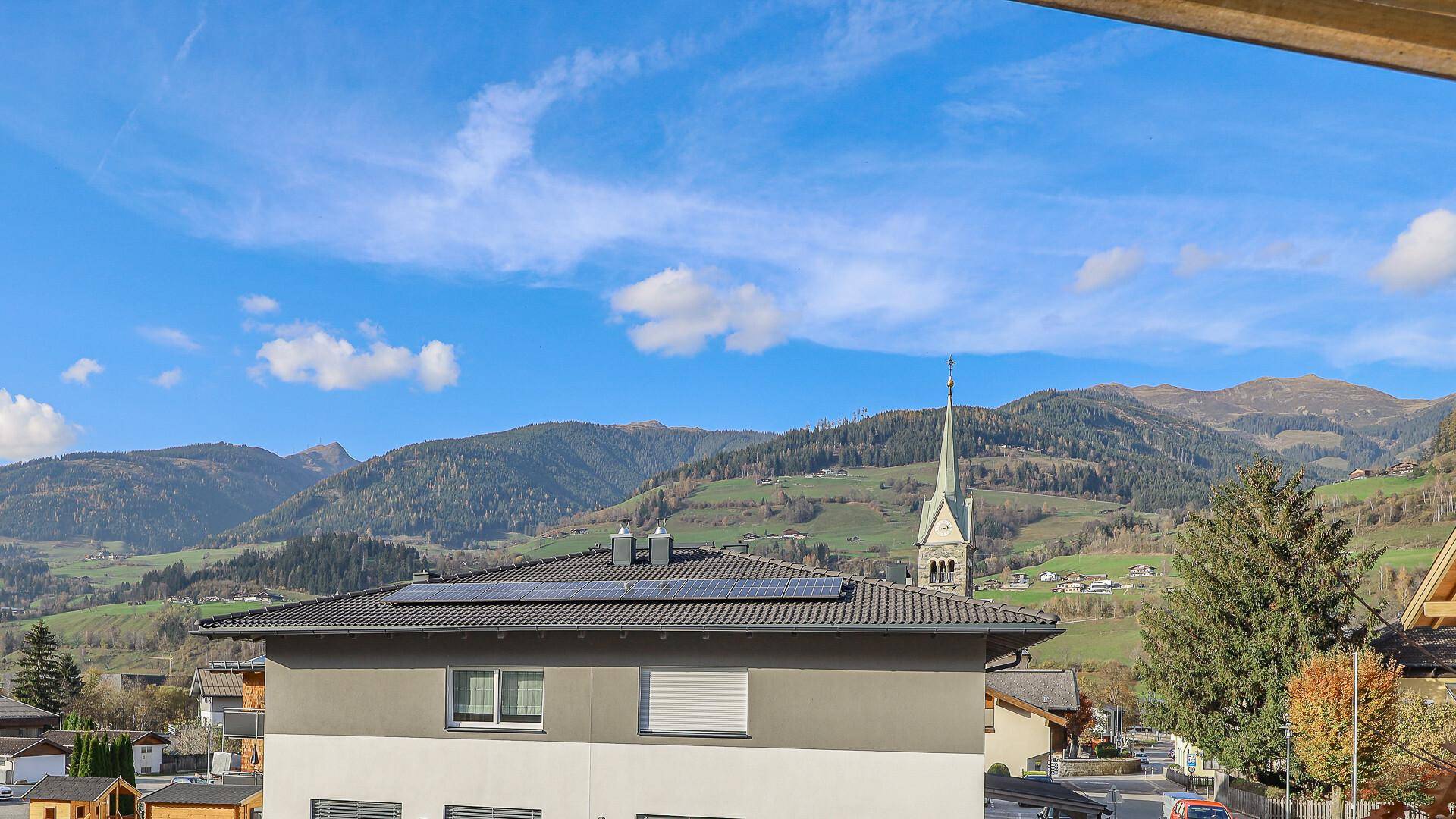 Panoramablick auf die Berglandschaft mit einem Kirchturm und umliegenden Häusern.