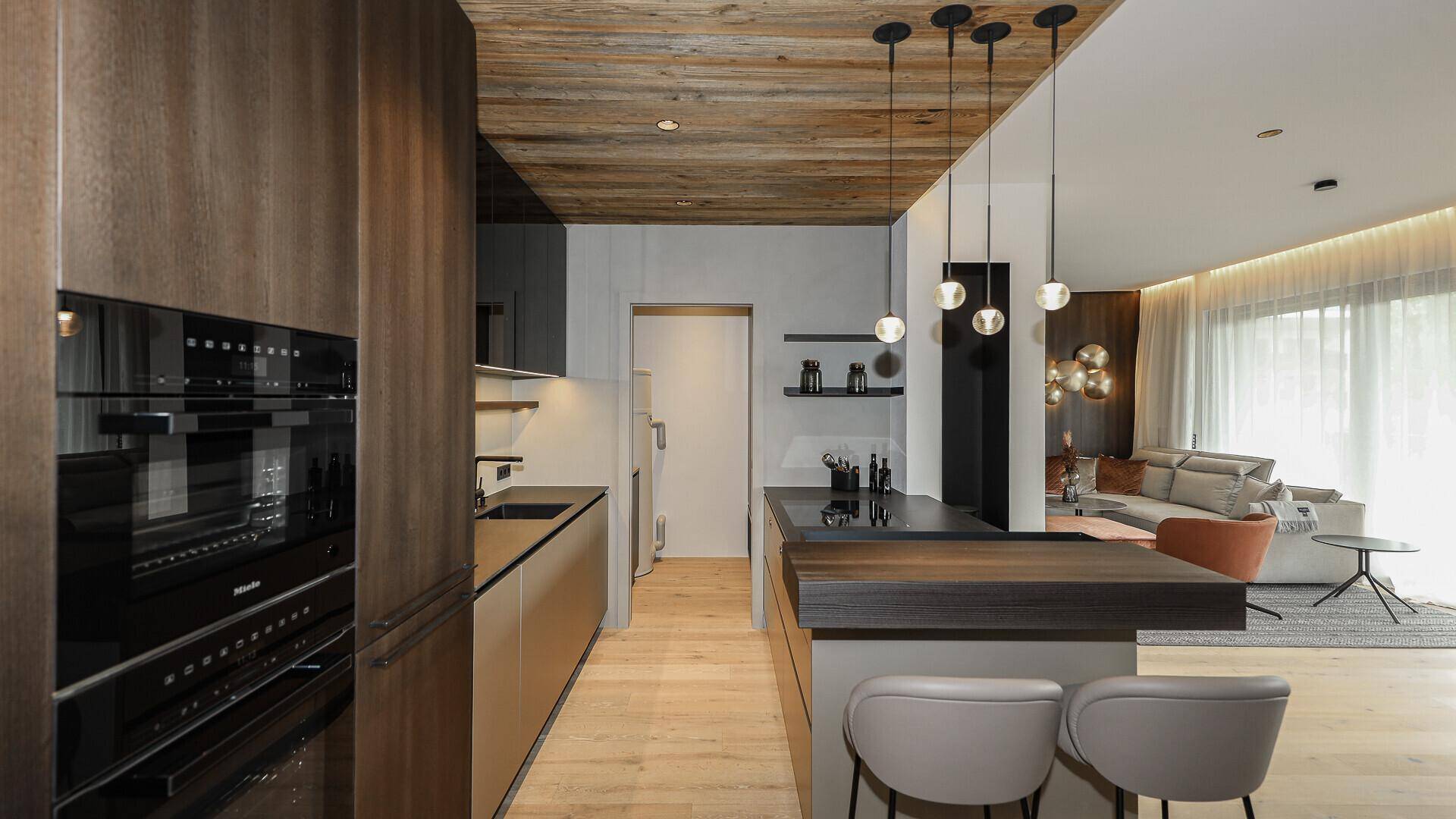 Elegante Küche mit Miele-Geräten, Holzdecke und offener Gestaltung zum Wohnbereich.