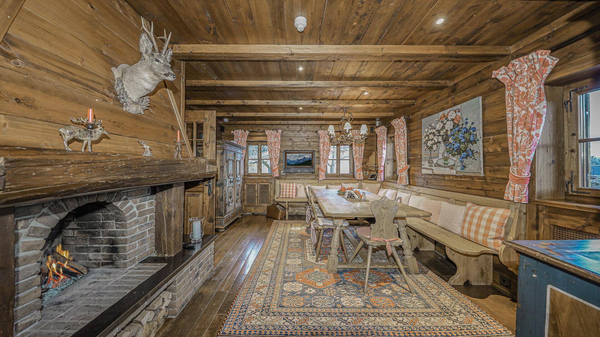 Traditioneller Essbereich mit Holztäfelung, Kamin und gemütlicher Eckbank im alpinen Stil.