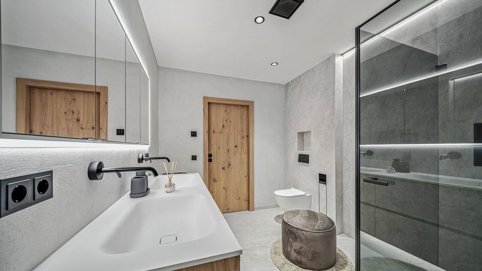 Modernes Badezimmer mit Doppelwaschbecken, Spiegelschrank, Toilette und begehbarer Dusche.