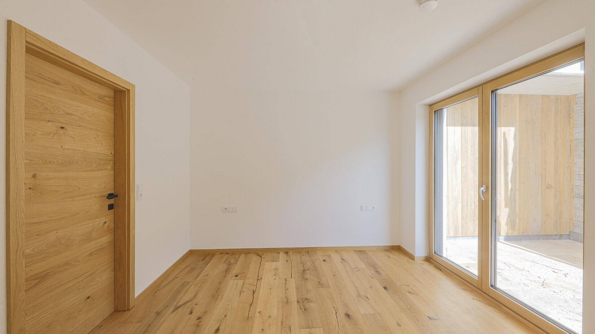 Heller Raum mit Holzboden und Zugang zu einem Außenbereich.