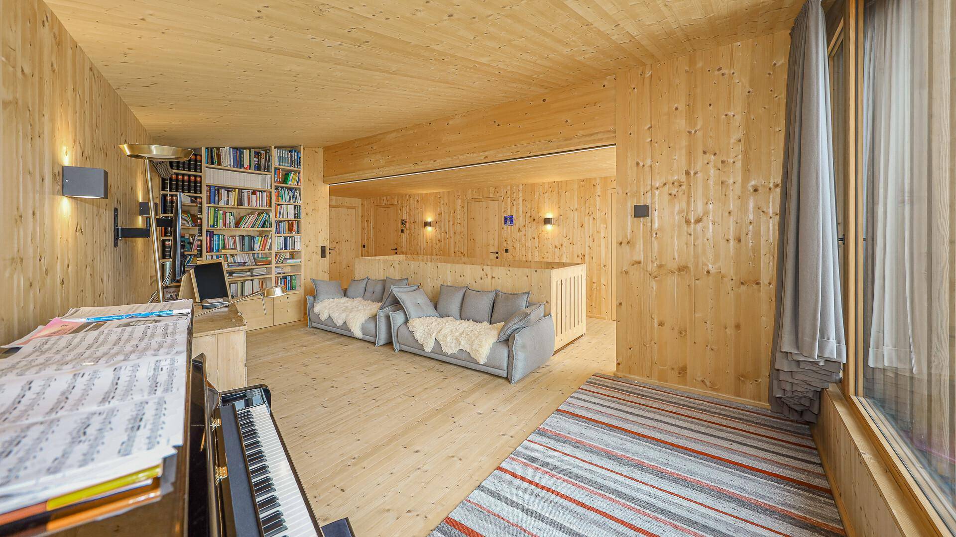 Geräumiger Wohnbereich mit Bücherregal, bequemen Sofas und Holzwänden, ideal zum Lesen und Entspannen.