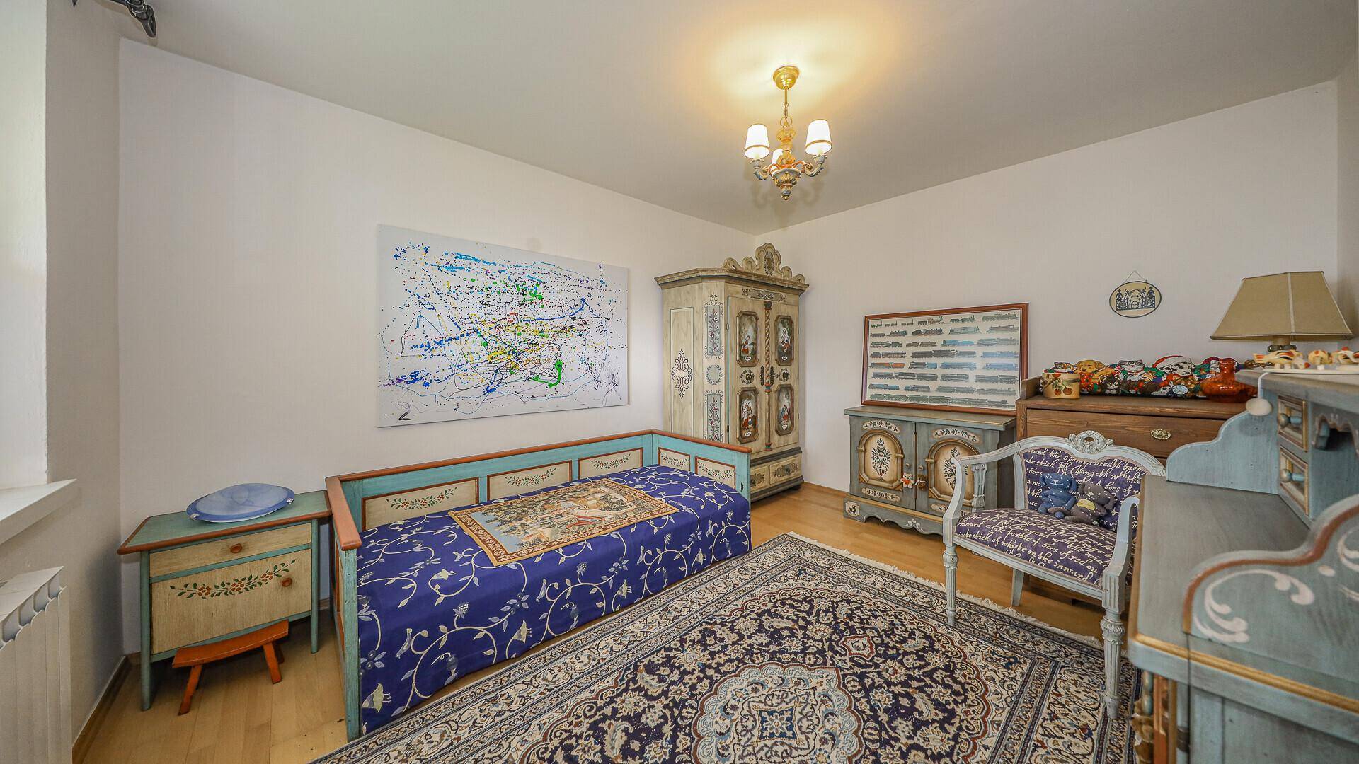 Schlafzimmer mit traditionellen Möbeln, Teppich, Parkettboden und farbenfroher Dekoration.