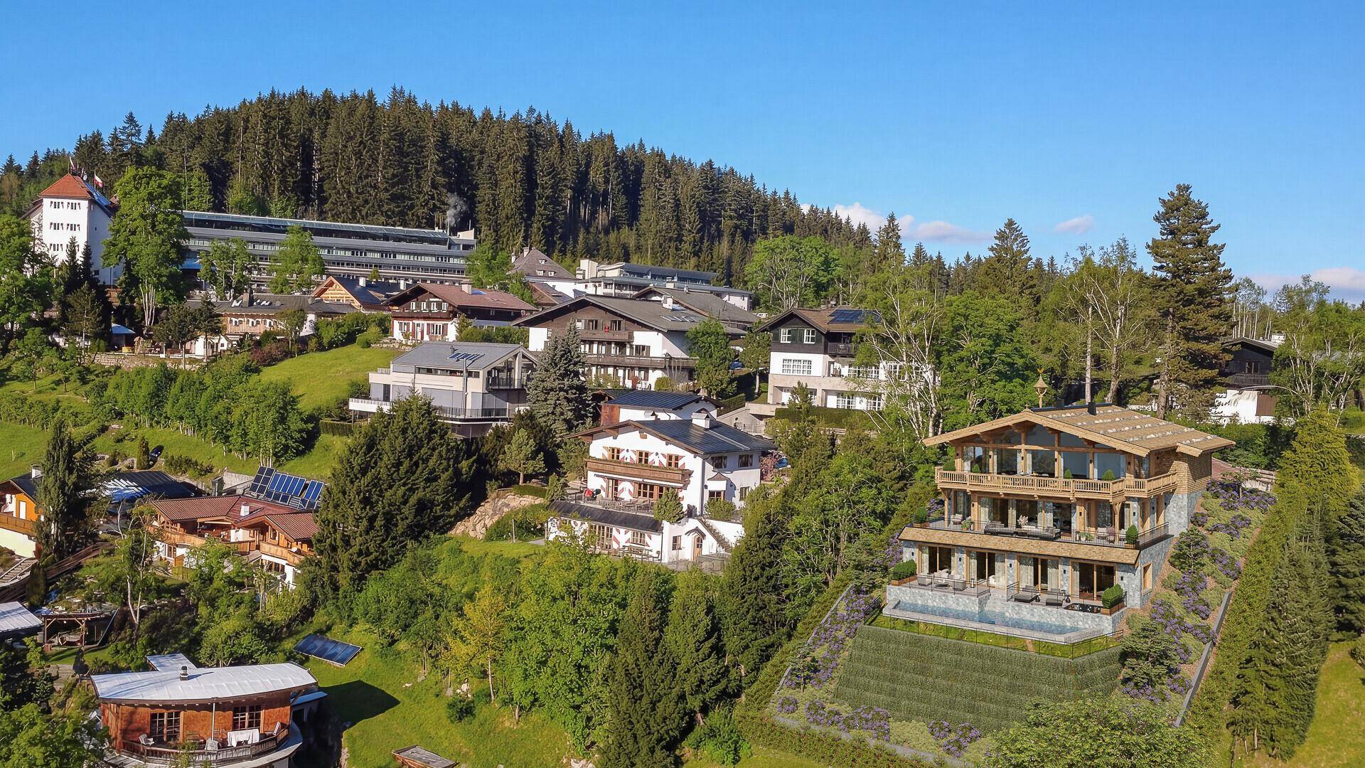 Panoramablick auf ein luxuriöses Alpenchalet in einer malerischen Berglandschaft mit umliegenden Häusern.