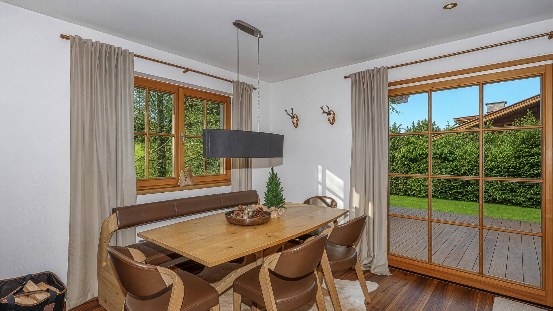 Heller Essbereich mit Holztisch, Sitzbank und großen Fenstern zum Garten.