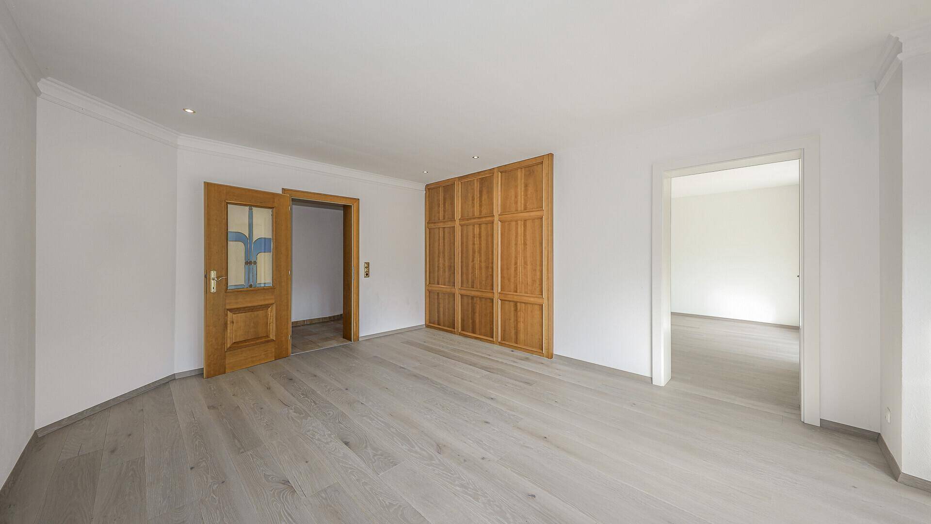 Heller Raum mit Holzboden, Holztüren und einer Holzwandverkleidung, die vielseitig nutzbar ist.