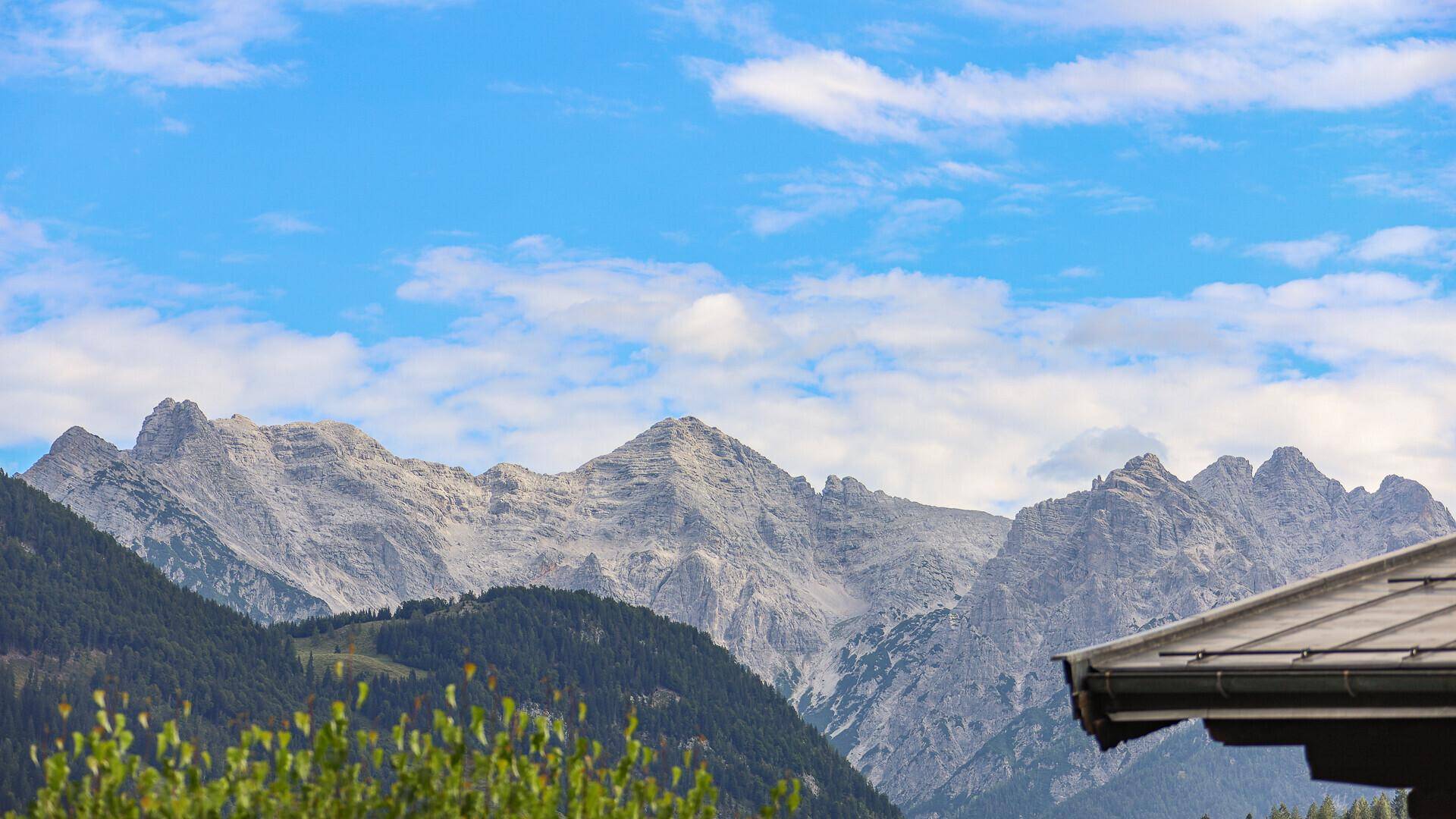 Majestätische Berglandschaft unter blauem Himmel mit weißen Wolken.