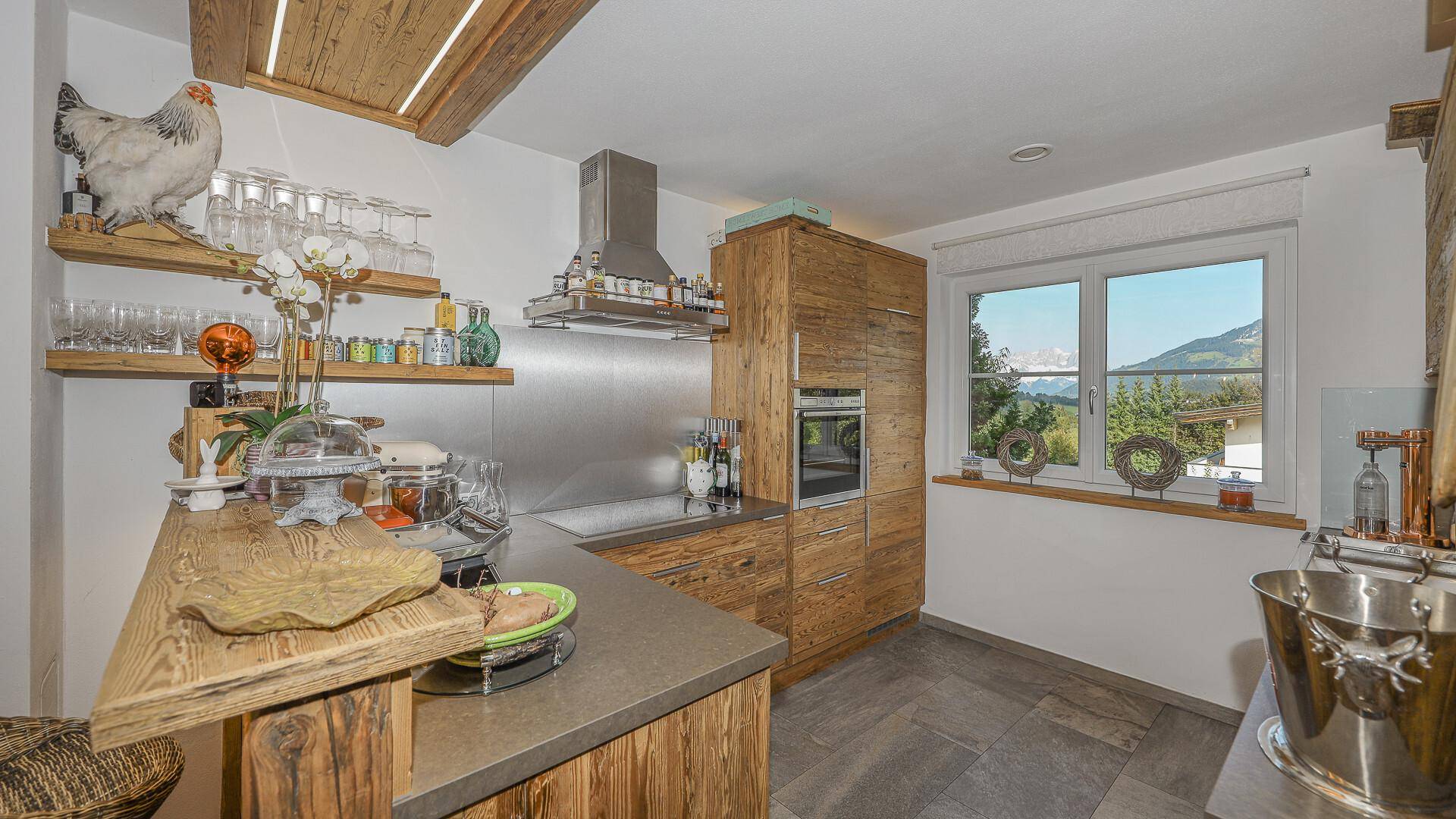 Rustikale Holzküche mit modernen Geräten, Stein-Arbeitsplatten und Fenster mit Bergblick.