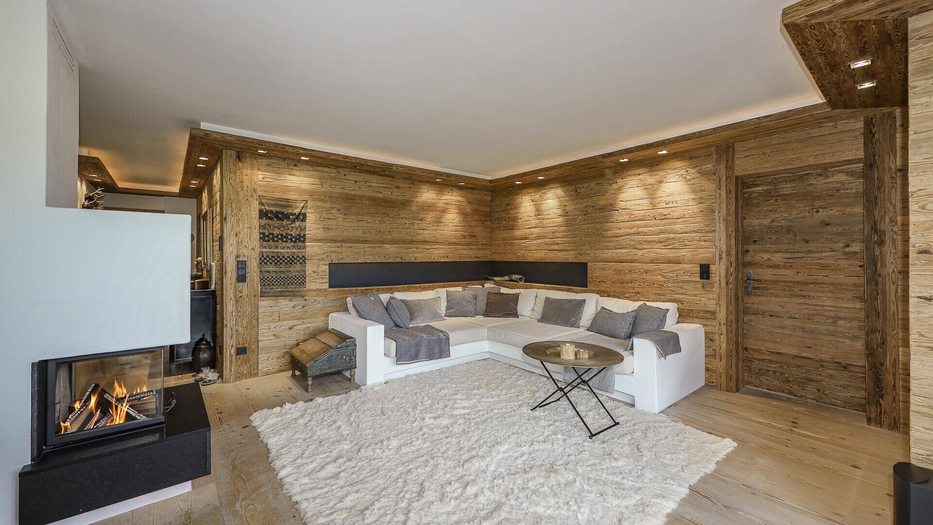 Gemütlicher Wohnbereich mit Holzwänden, Kamin und weichem Teppich, ideal zum Entspannen.