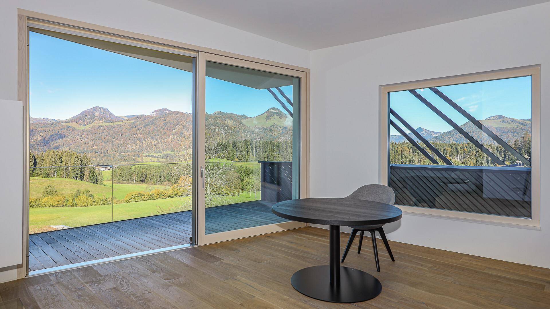 Essbereich mit Holzboden und großen Fenstern, die einen weiten Blick auf die Berge bieten.