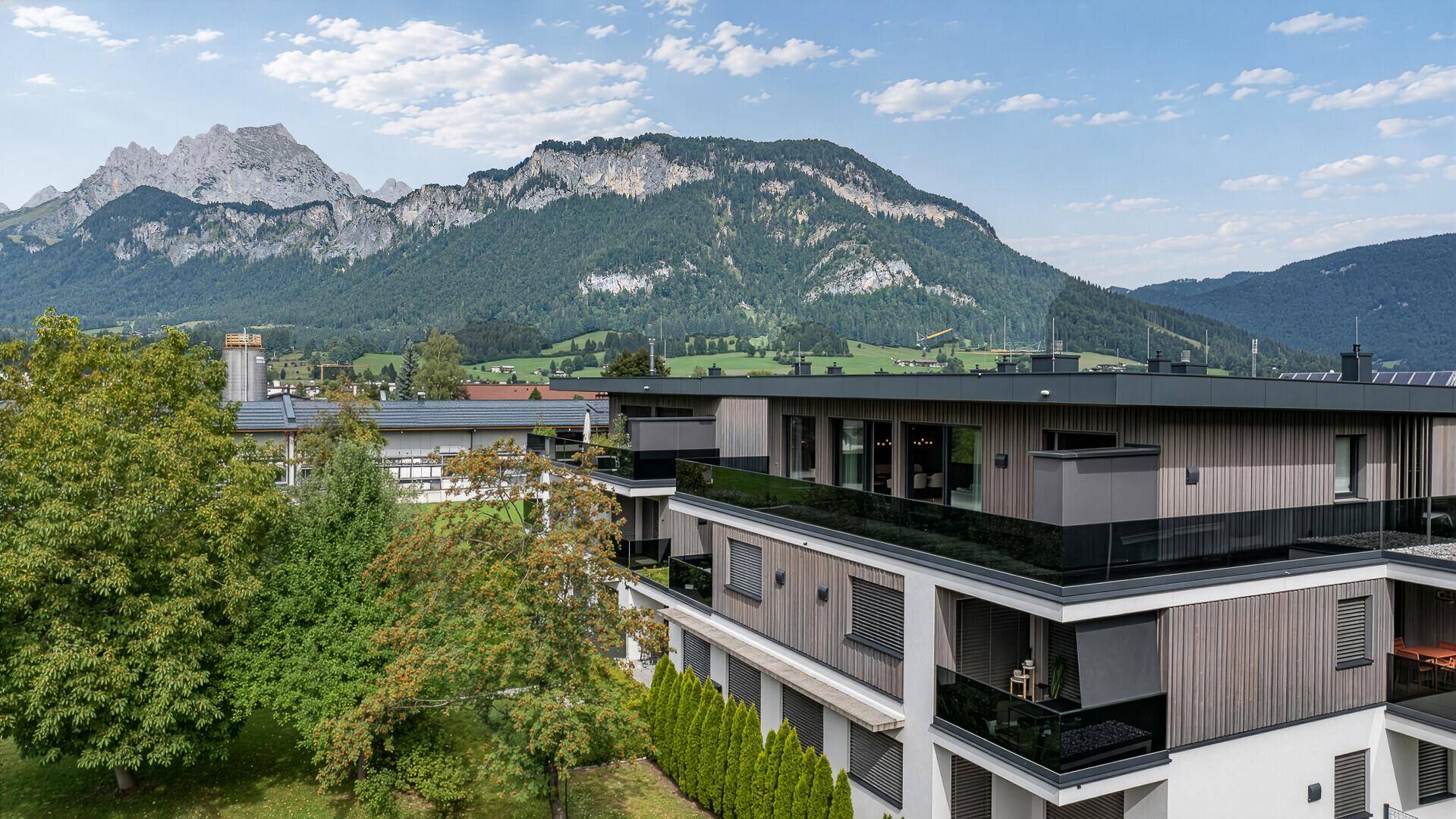 Neubau mit moderner Architektur, Holzfassade und weitem Blick auf die umliegende Berglandschaft.