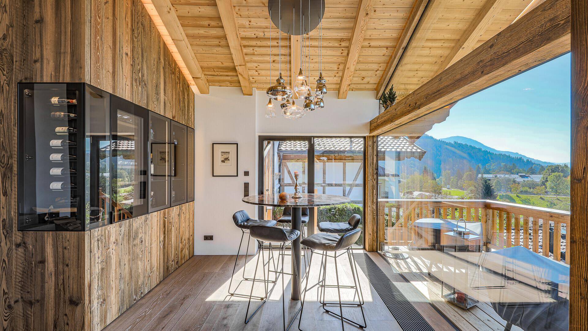 Heller Essbereich mit Holzwänden, Bartisch und Zugang zum Balkon mit schöner Aussicht.