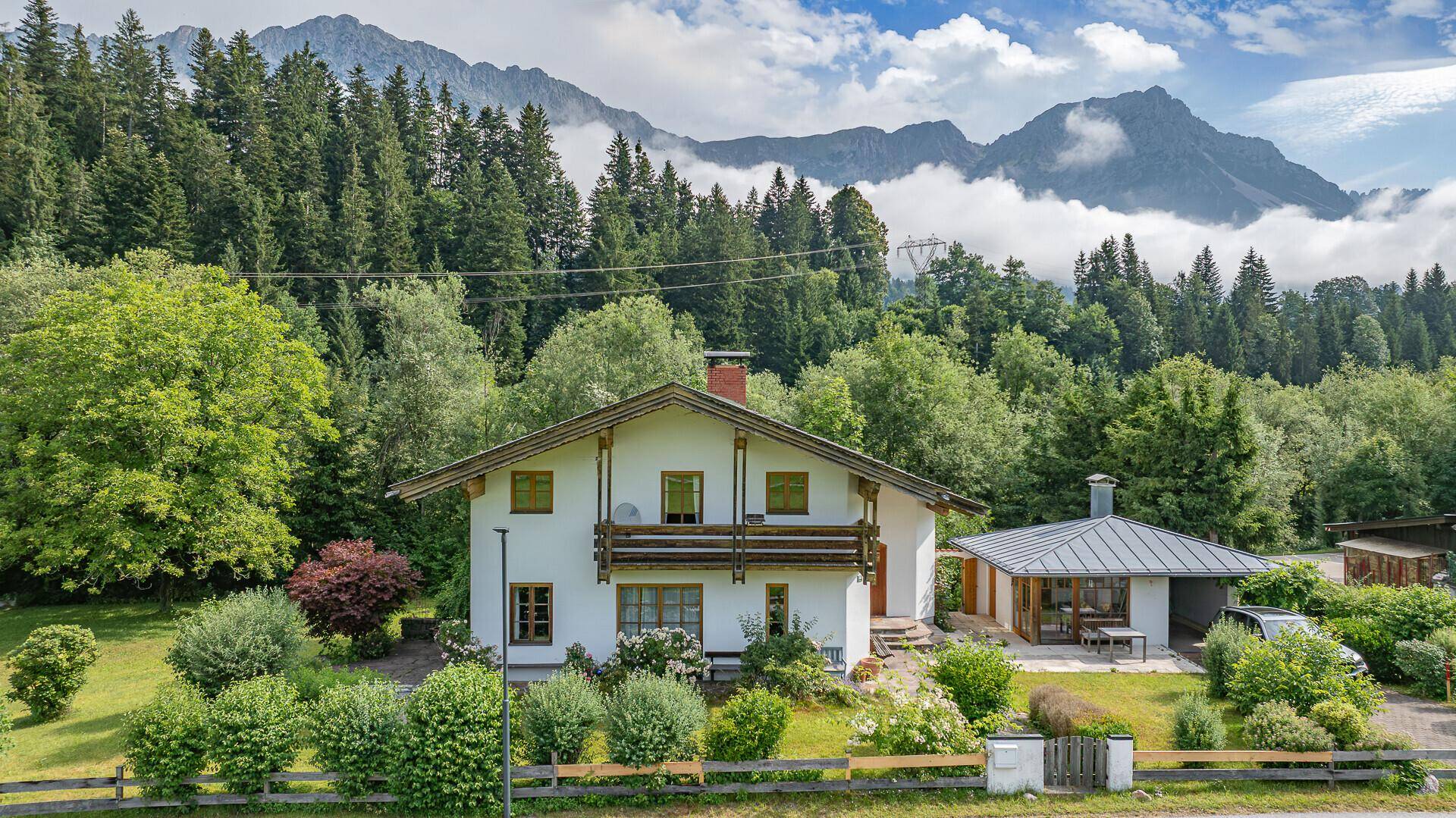 Charmantes Einfamilienhaus mit Holzbalkonen und weitläufigem Garten, eingebettet in eine malerische Berglandschaft.