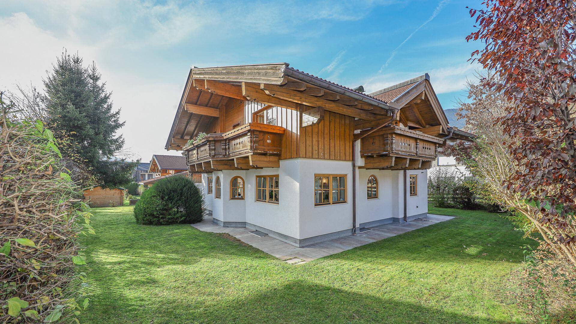 Rückansicht des Hauses mit großem Rasenbereich und traditionellen Holzbalkonen.
