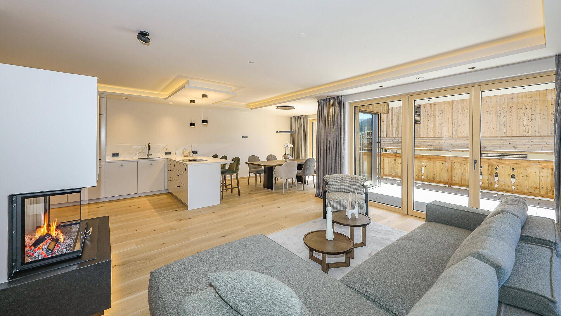 Heller Wohnbereich mit Kamin, Holzboden und Zugang zu einem großen Balkon.