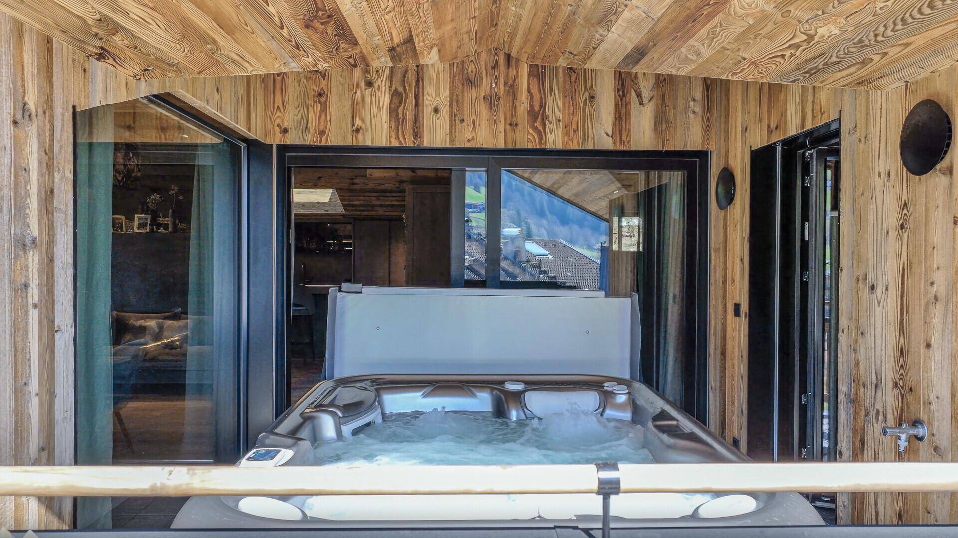 Überdachter Balkon mit Whirlpool und Zugang zu den Innenräumen des Chalets.