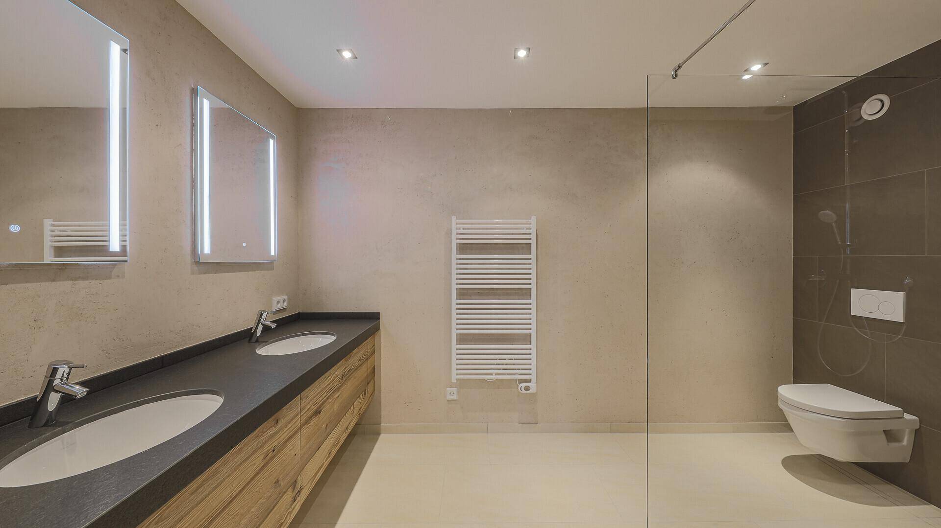 Elegantes Badezimmer mit Doppelwaschbecken, wandhängendem WC und großer Duschkabine.
