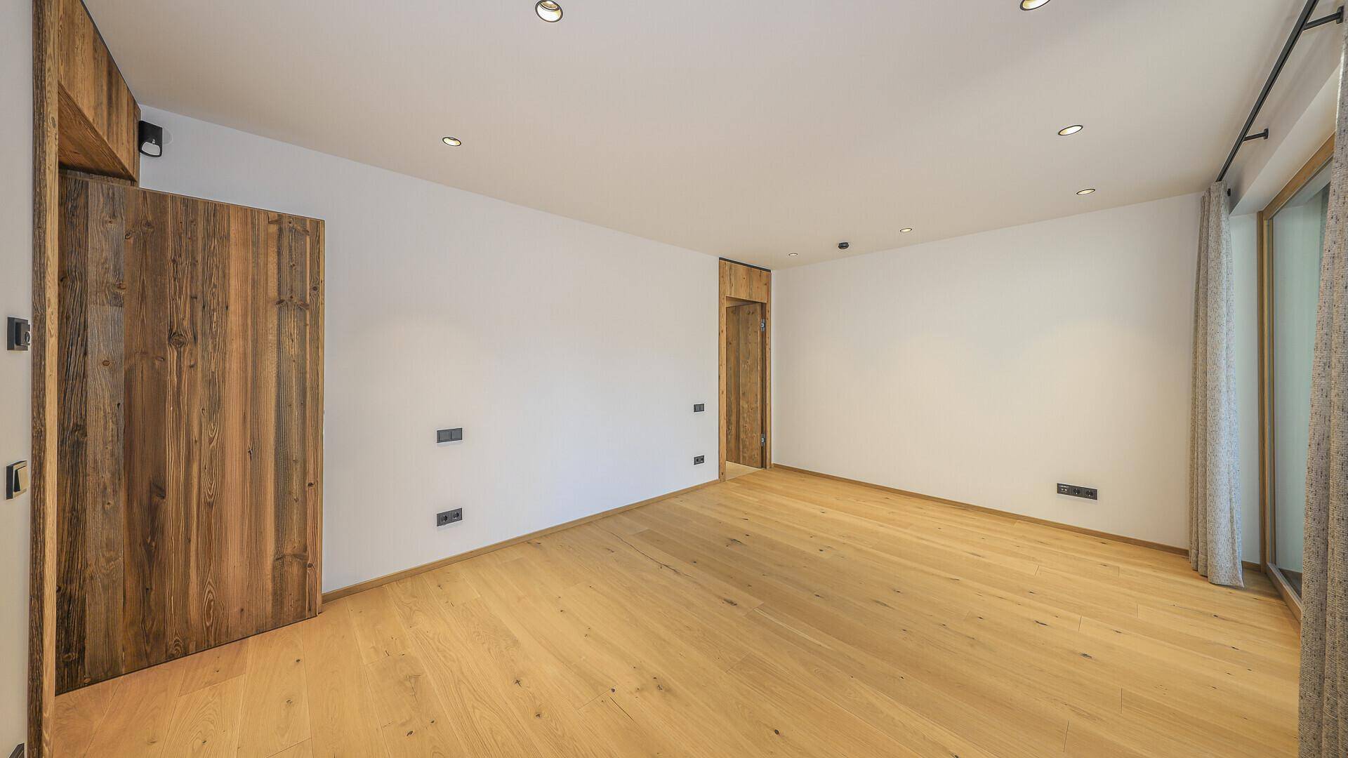 Helles Schlafzimmer mit Holzboden und weiß gestrichenen Wänden, bereit zur individuellen Gestaltung.