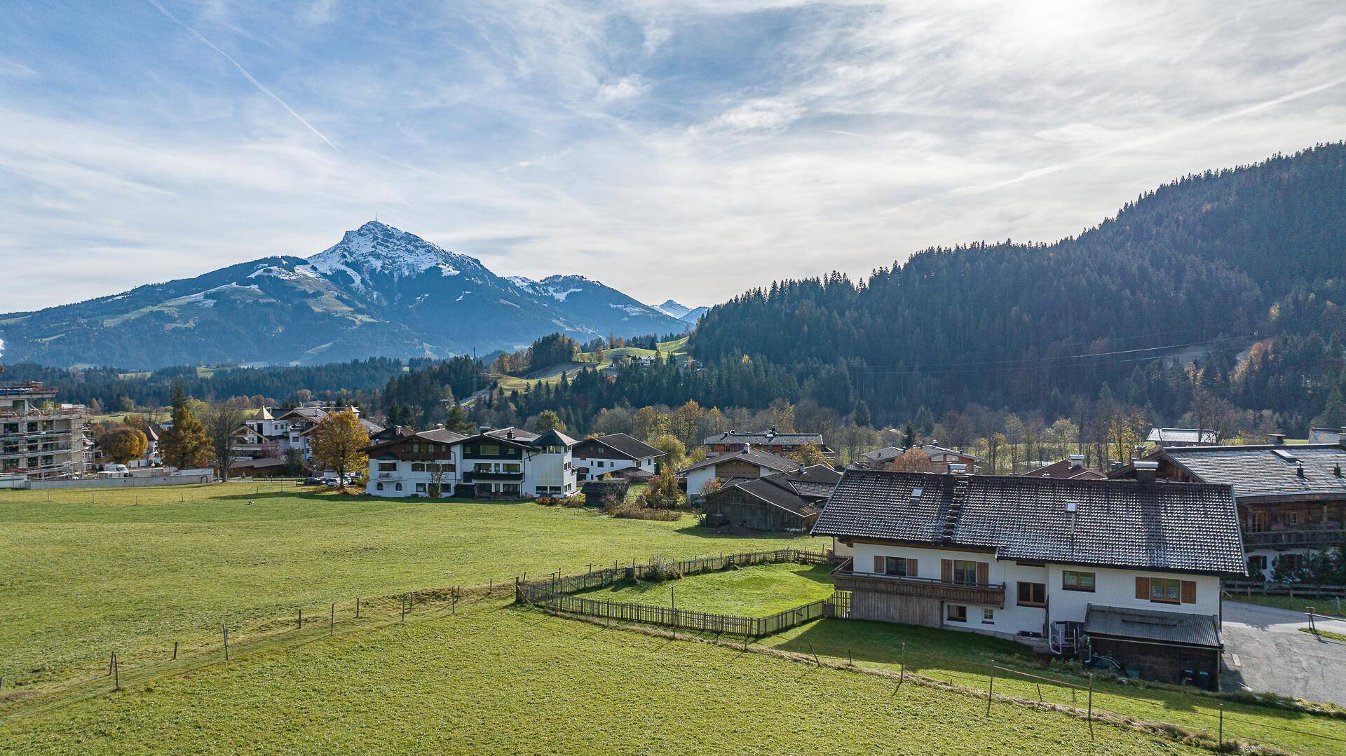 Haus in idyllischer Lage umgeben von grünen Wiesen und einem majestätischen Bergpanorama.