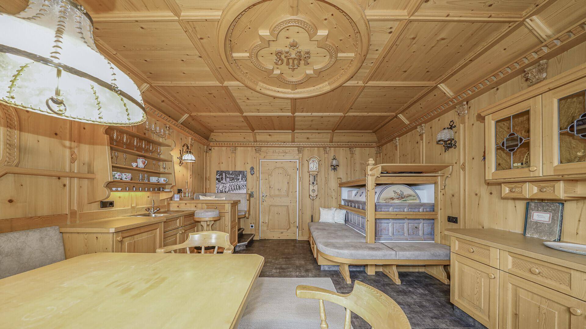 Gemütlicher Wohnbereich im Landhausstil mit Holztäfelung, Esstisch und Alkovenbett.