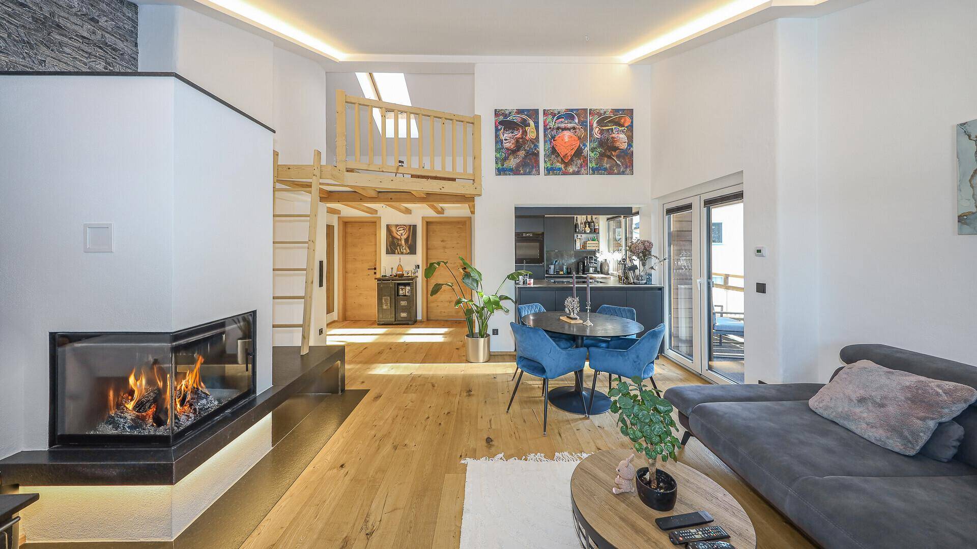 Geräumiger Wohnbereich mit Kamin, Holzboden und Zugang zu einem Balkon.
