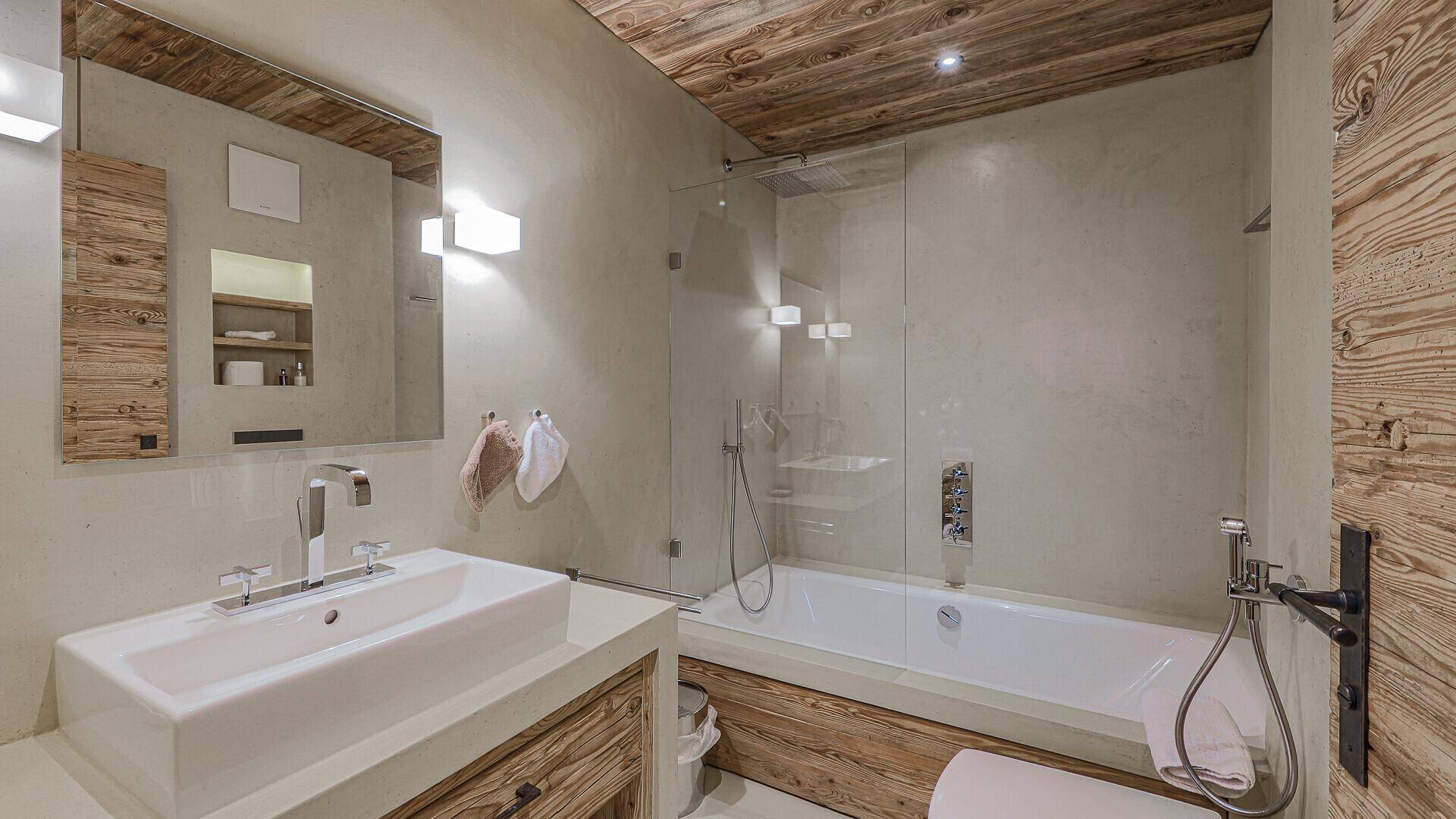 Modernes Badezimmer mit Badewanne, Dusche, Einzelwaschbecken und Holzdecke.