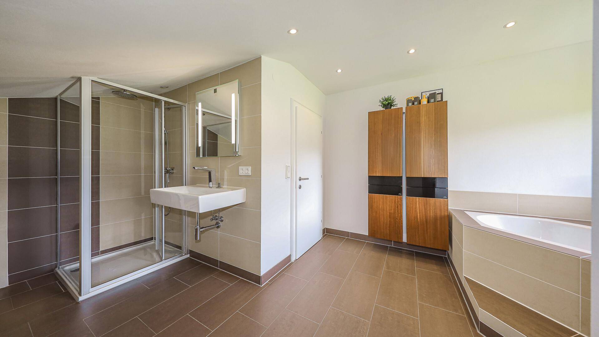 Geräumiges Badezimmer mit Duschkabine, modernem Waschbecken und Fliesenboden.