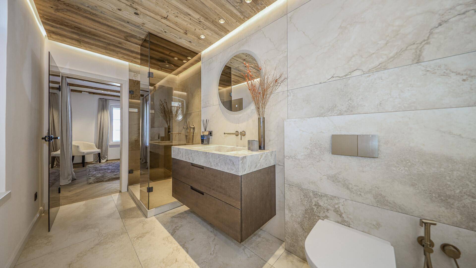 Modernes Badezimmer mit Marmorfliesen, Einzelwaschbecken und begehbarer Dusche.